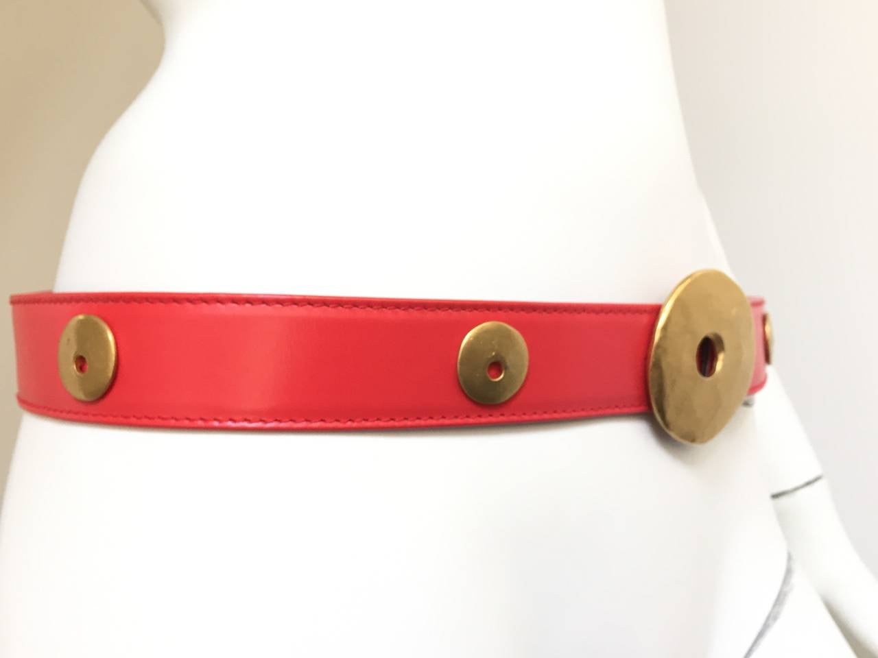 Escada 80s red leather with brass abstract circular shapes is a German size 42 which is an USA size 12. There are two holes on strap. 
Measurements are:
36