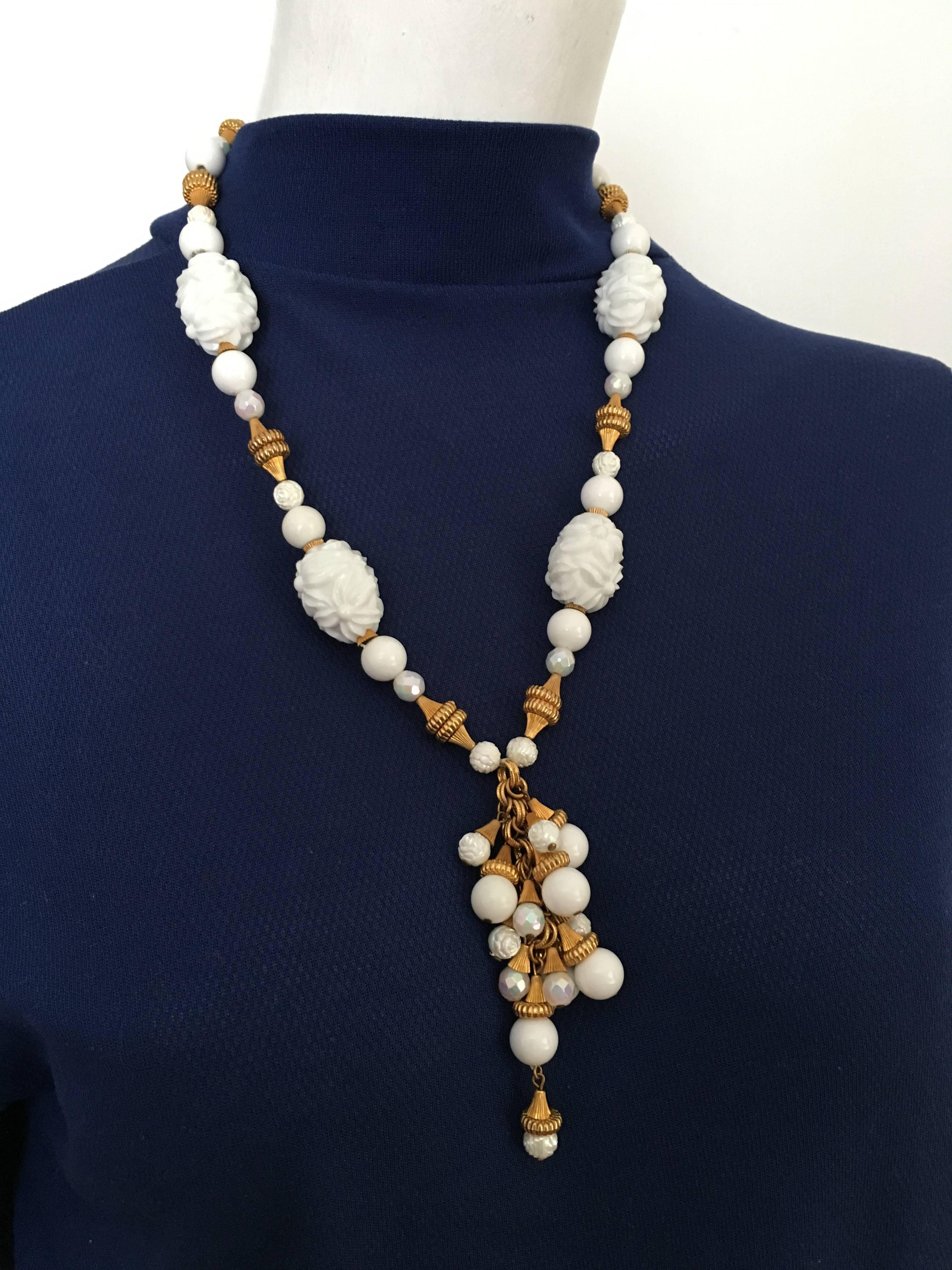 Hattie Carnegie 1950s necklace with tassel pendant white & gold beads.  The large white beads have flower patterns.  This 1950s necklace was never worn and still has the original tag with price on it.  The original value to this necklace was $10