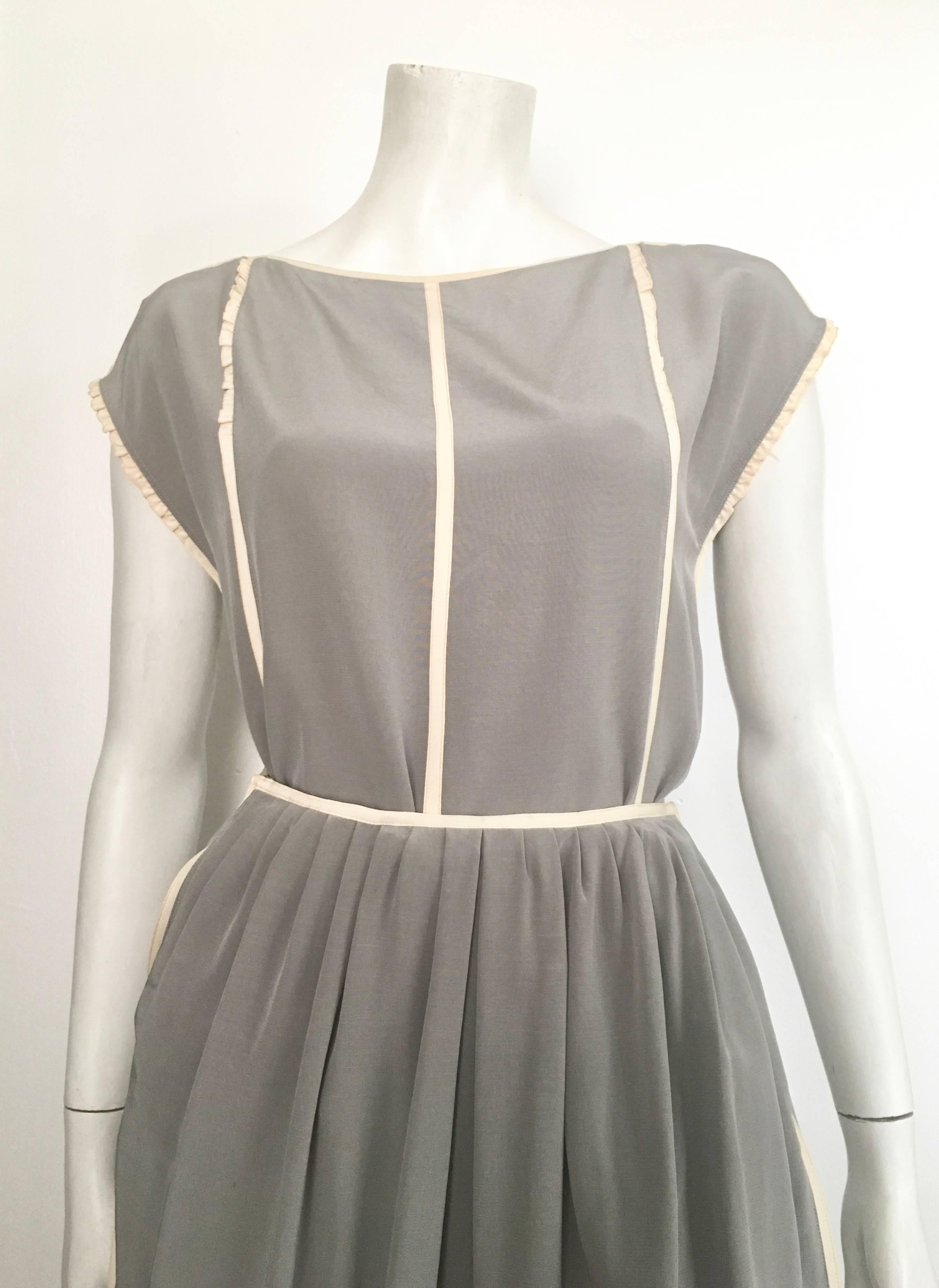 Geoffrey Beene for Neiman Marcus 1970s two piece set grey silk with cream trim short sleeve blouse & pleated skirt with pockets is labeled a vintage size 8 but fits like a modern size 2.  The waist on this skirt is 22. 1/2