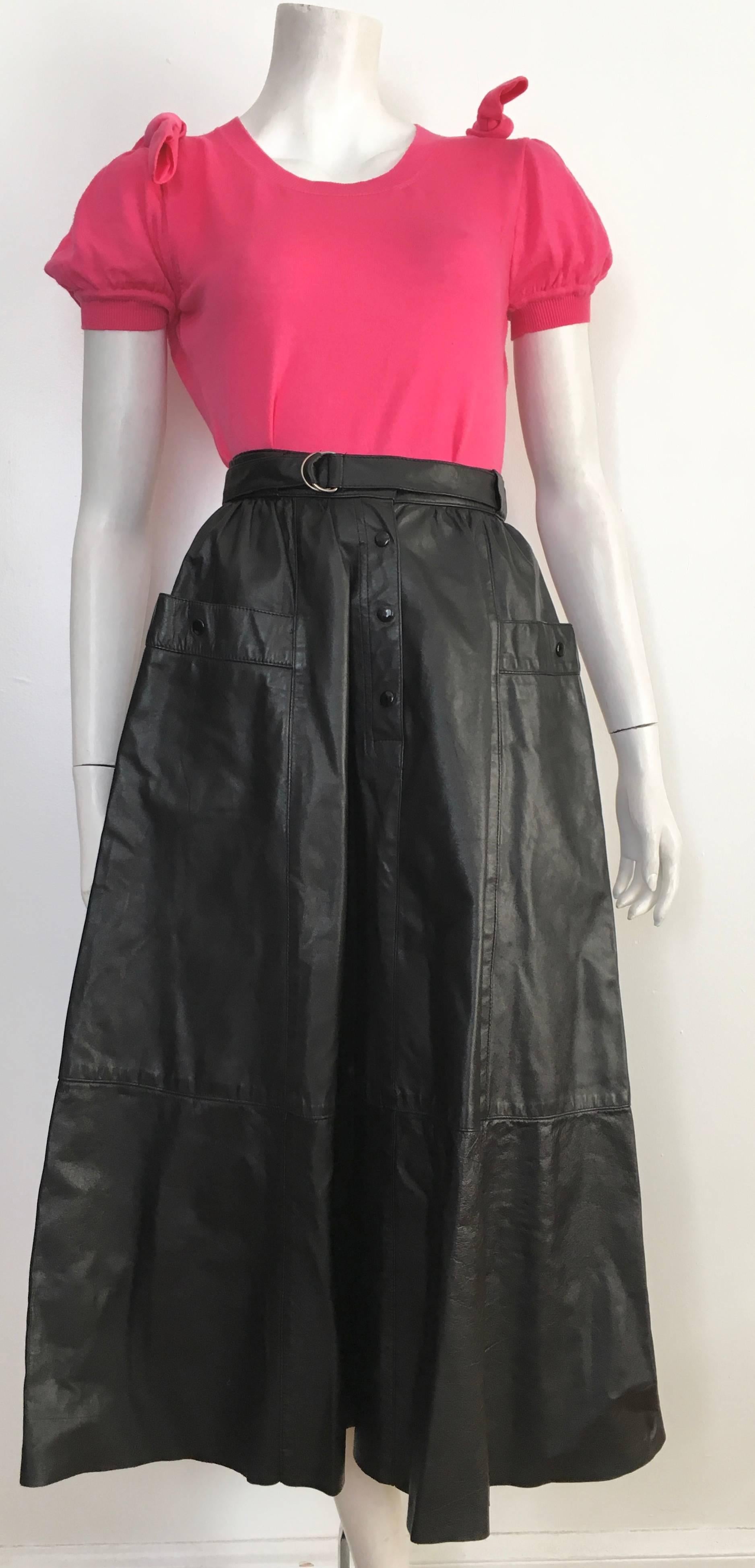 Saks Fifth Avenue 1980s black leather snap button long A Line skirt with pockets is  labeled a size 6 but fits a size 4. The waist on this skirt is 27