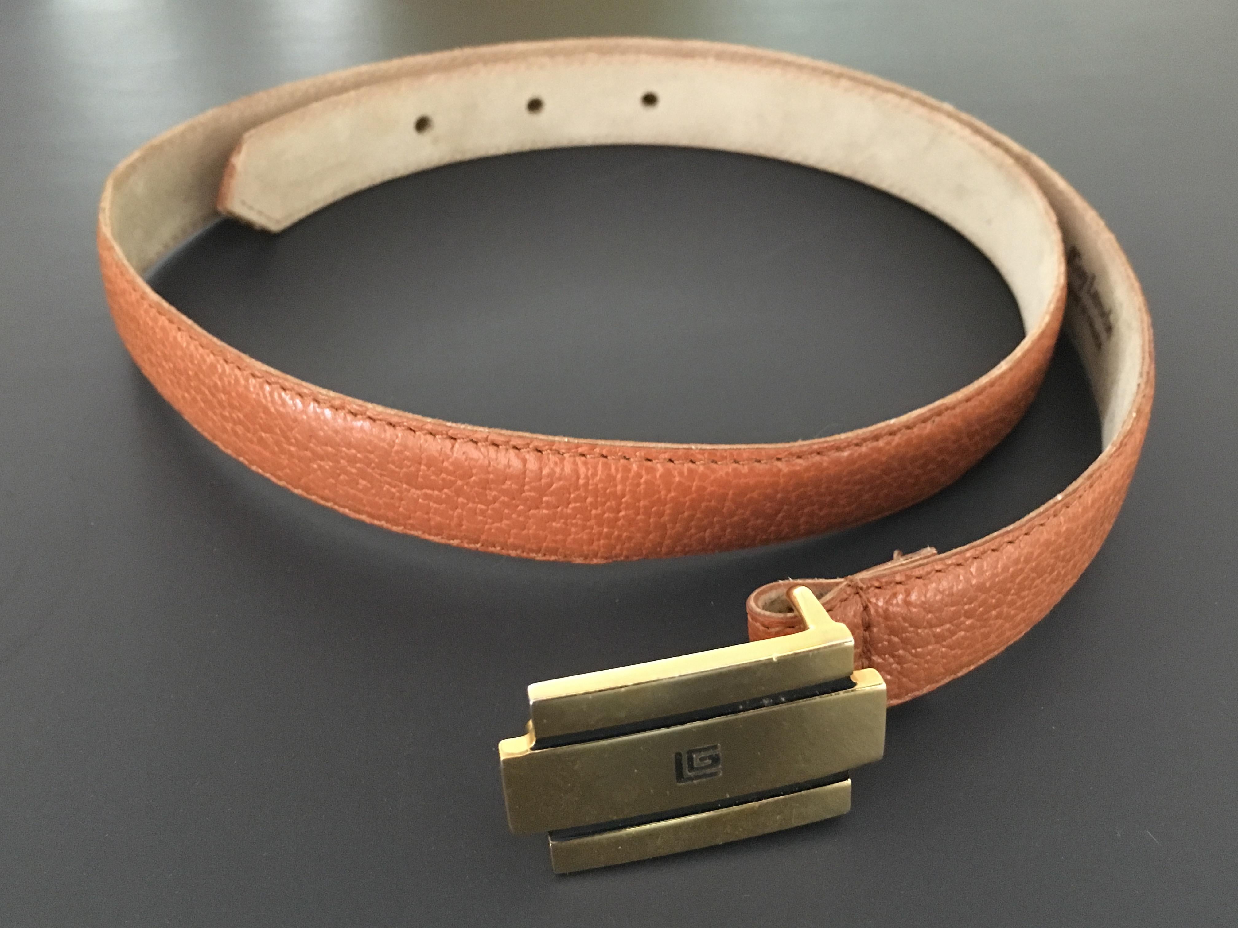 Guy Laroche 1990s tan leather belt with brass buckle with logo is a size small 2 / 4. This belt looks amazing worn high waisted.  Back side of belt is suede. There are a few very tiny black dots on the belt strap near buckle as shown in photo but