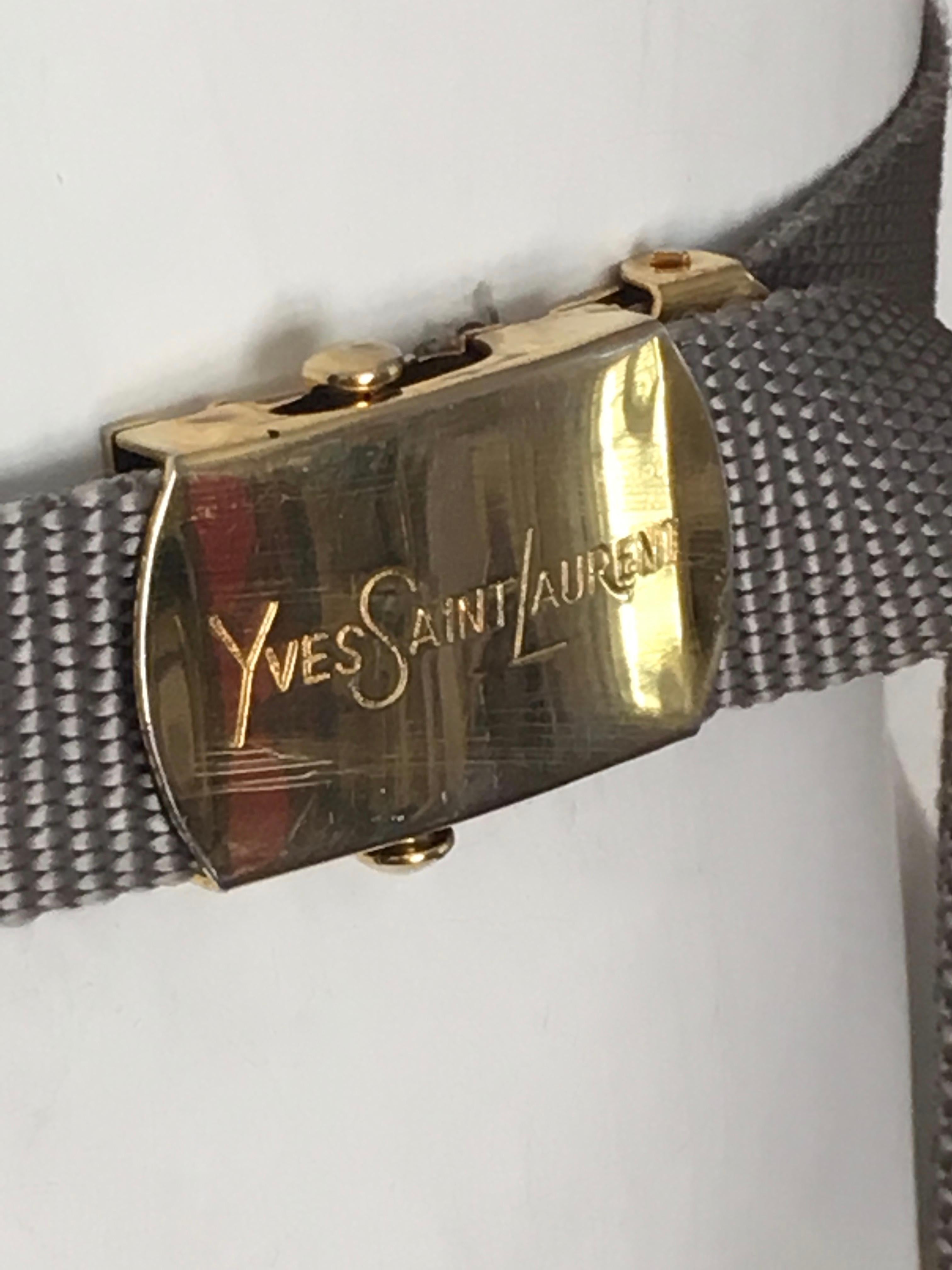 Yves Saint Laurent 1980s grey nylon woven strap with brass buckle belt is a size small.  This belt will fit an USA size 2 / 4.  This YSL nylon adjustable belt buckle has some age, as shown in photo but it is from the 80s and is consistent with age &