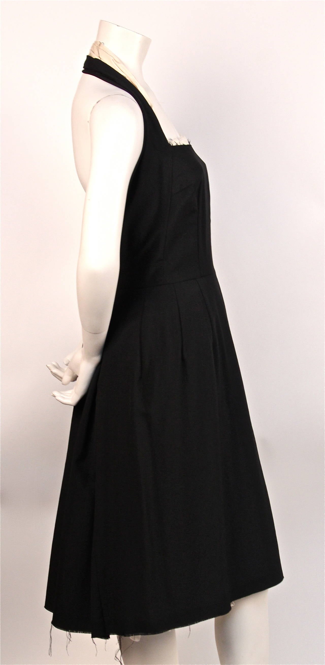 Very rare jet black cotton pinafore style halter dress with raw edges and unique muslin lining from Comme Des Garcons dating to 1997. Size 'S'. Approximate measurements: bust 32-34