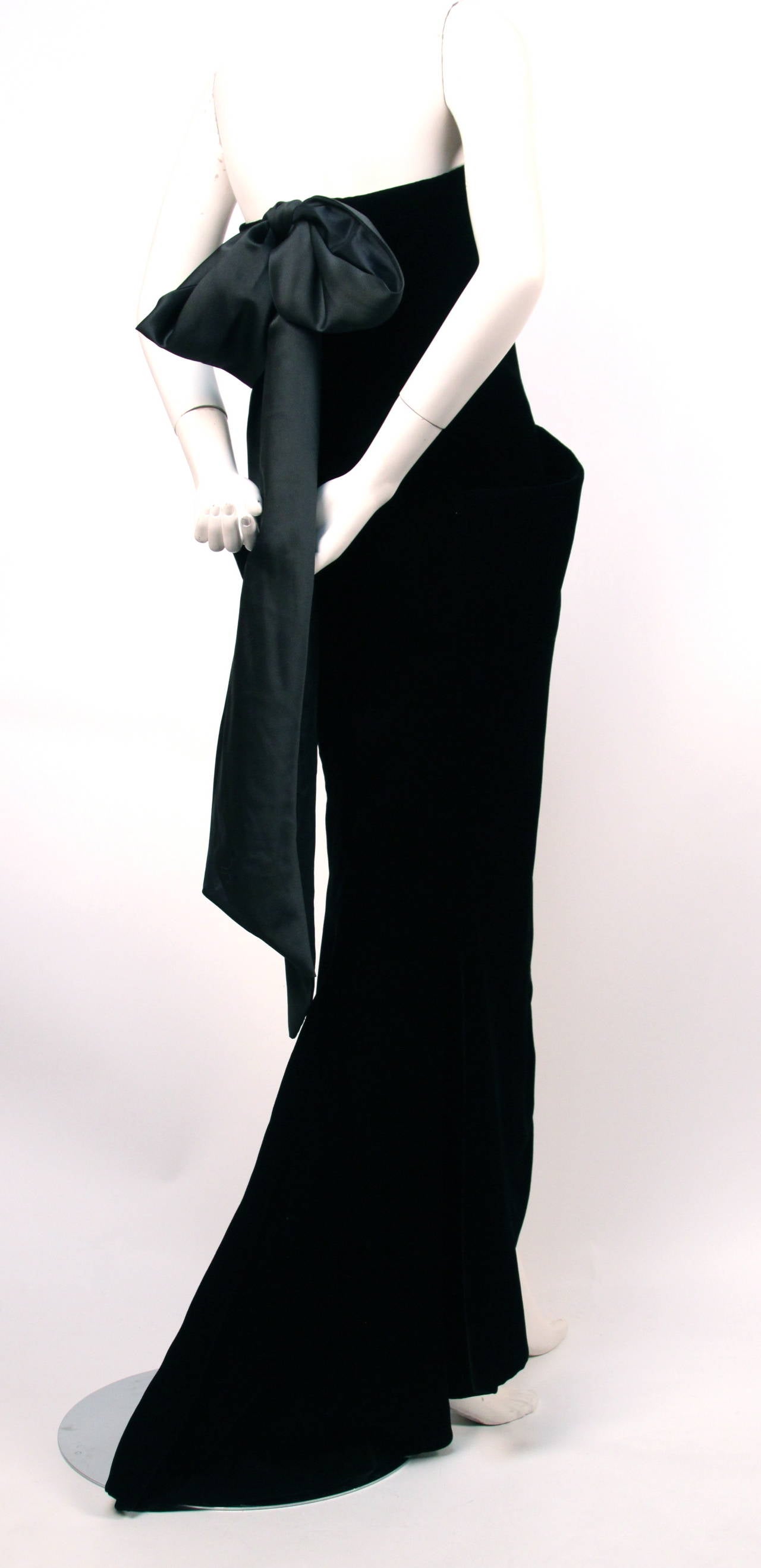 Jet black velvet haute couture gown with large wrap around pockets, high front slit and satin bow at back from Christian Dior designed by Marc Bohan dating to the fall of 1986. Best fits a US size 4. Approximate measurements: bust 32-33