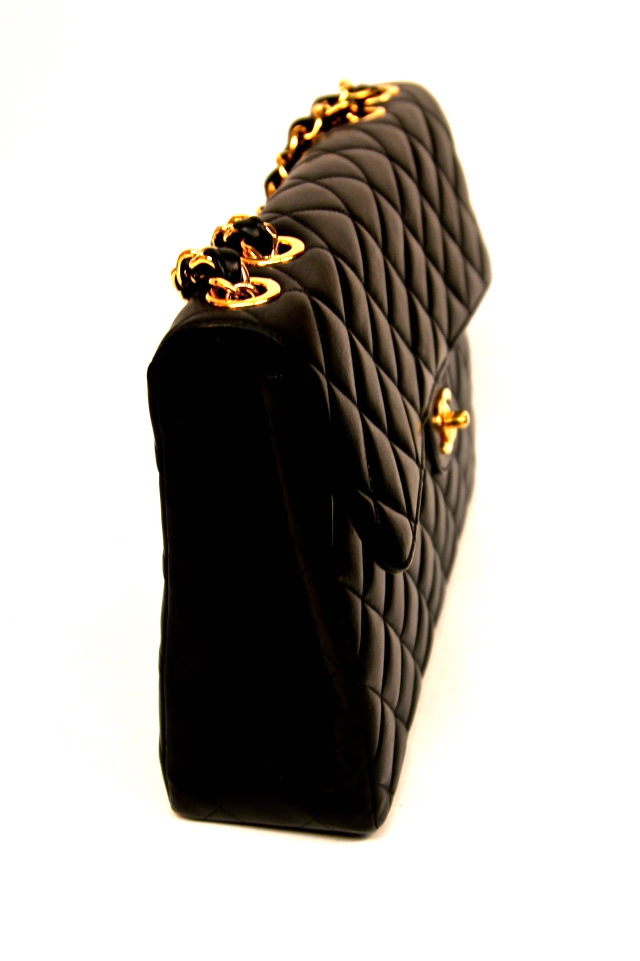 Classic jet black quilted leather flap bag with shiny gilt chain woven with leather and gilt CC turn-lock from Chanel dating to the 1990's. Approximate measurements: height 9