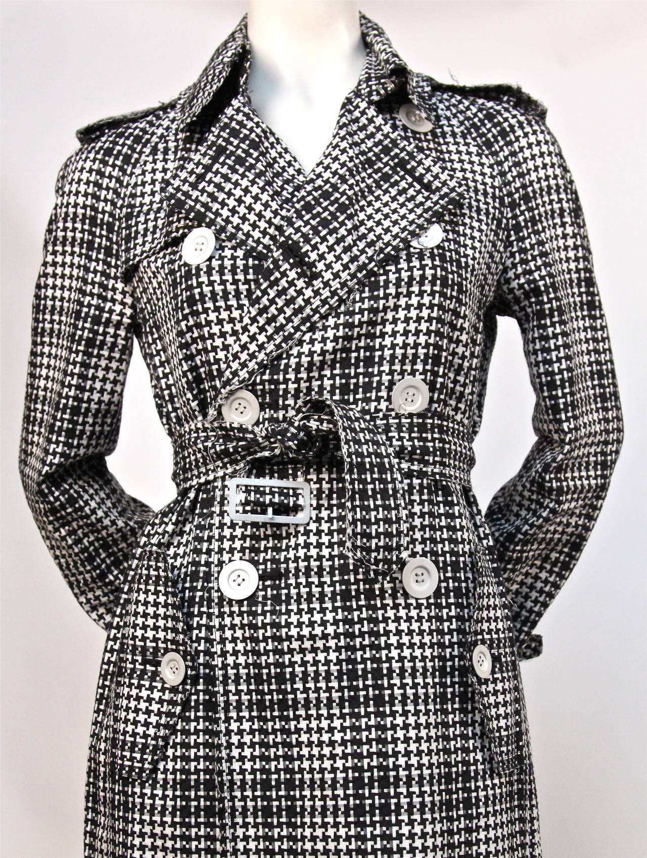 Black and white woven houndstooth check trench coat with unfinished edges and silver buttons from Junya Watanable for Comme des Garcons dating to spring of 2003. Labeled a size 'M'. Approximate measurements: shoulders 15-16