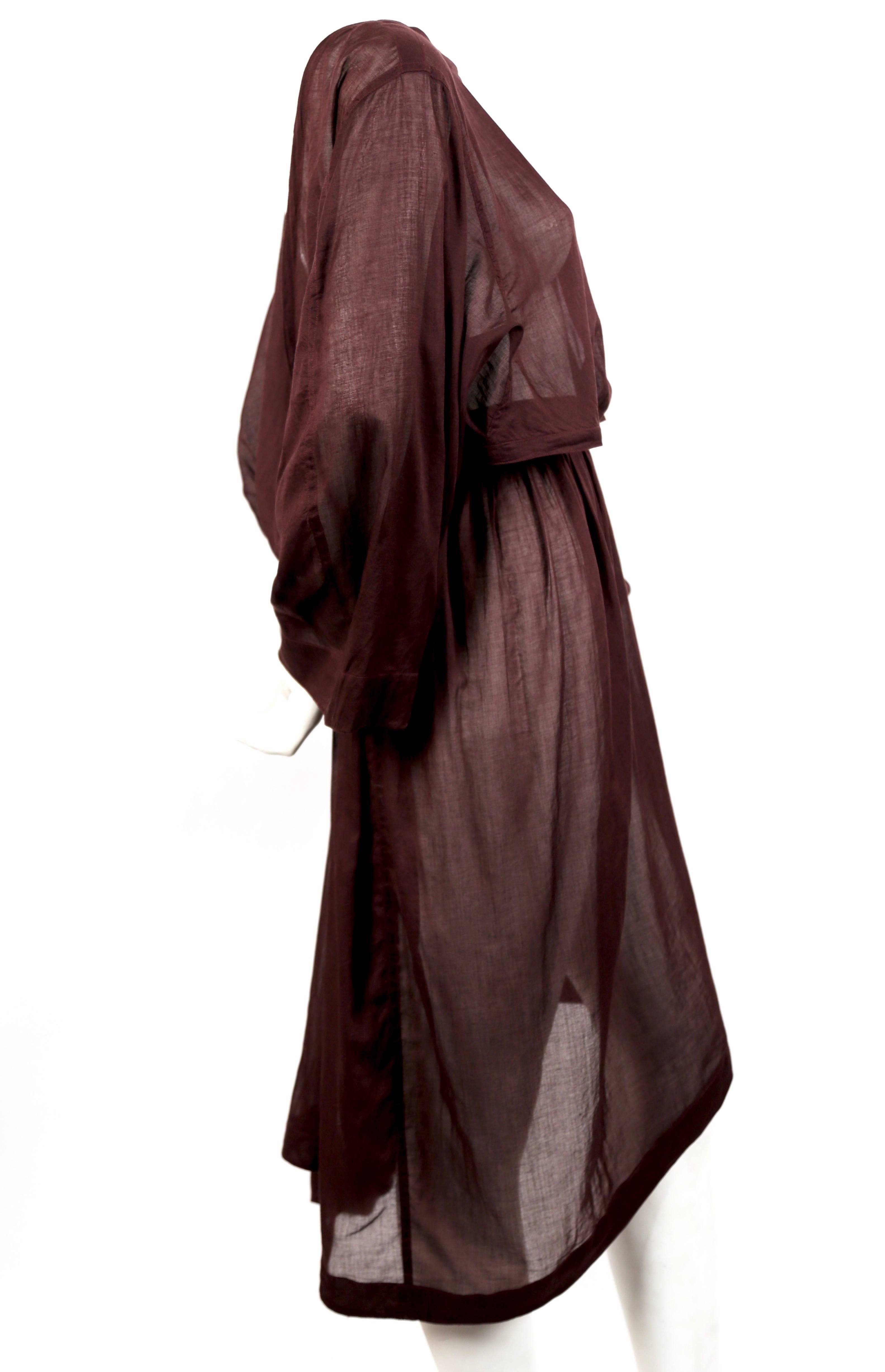 Very rare burgundy colored sheer cotton dress with draping at waist and at back and unique, asymmetrical cut-out designed by Azzedine Alaia dating to the late 1980's. Labeled a French size 38 although this will fit a 24