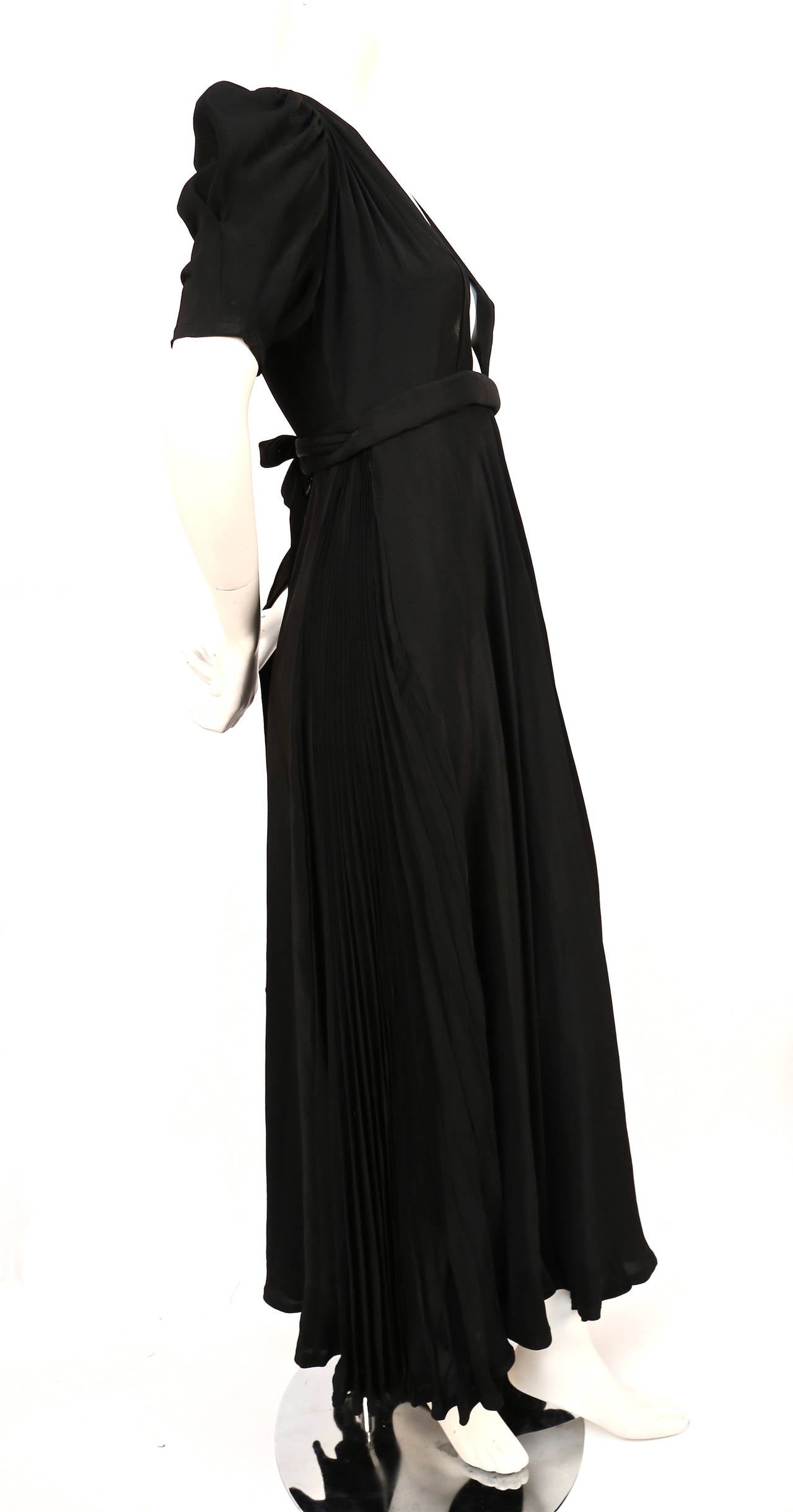 A jet black silk crêpe 'Bridget' dress designed by Ossie Clark for Quorum dating to 1970.  Labelled 'Ossie Clark, size 10', with plunging neckline, wrap-over skirt with knife-pleated side panels. Bust measures approximately 32