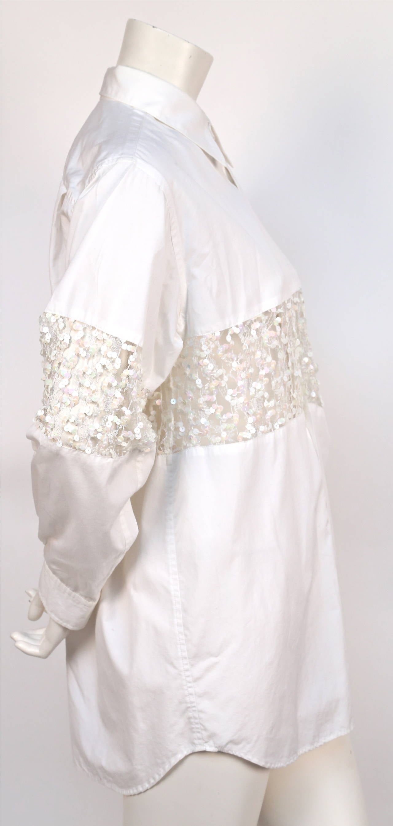 Very rare white cotton button up shirt with sheer sequined panel and peekaboo  pleat at bust designed by Rei Kawakubo for Comme Des Garcons dating pre-1988.  Size 'S' however this is an oversized shirt and would easily fit a medium. Made in Japan.