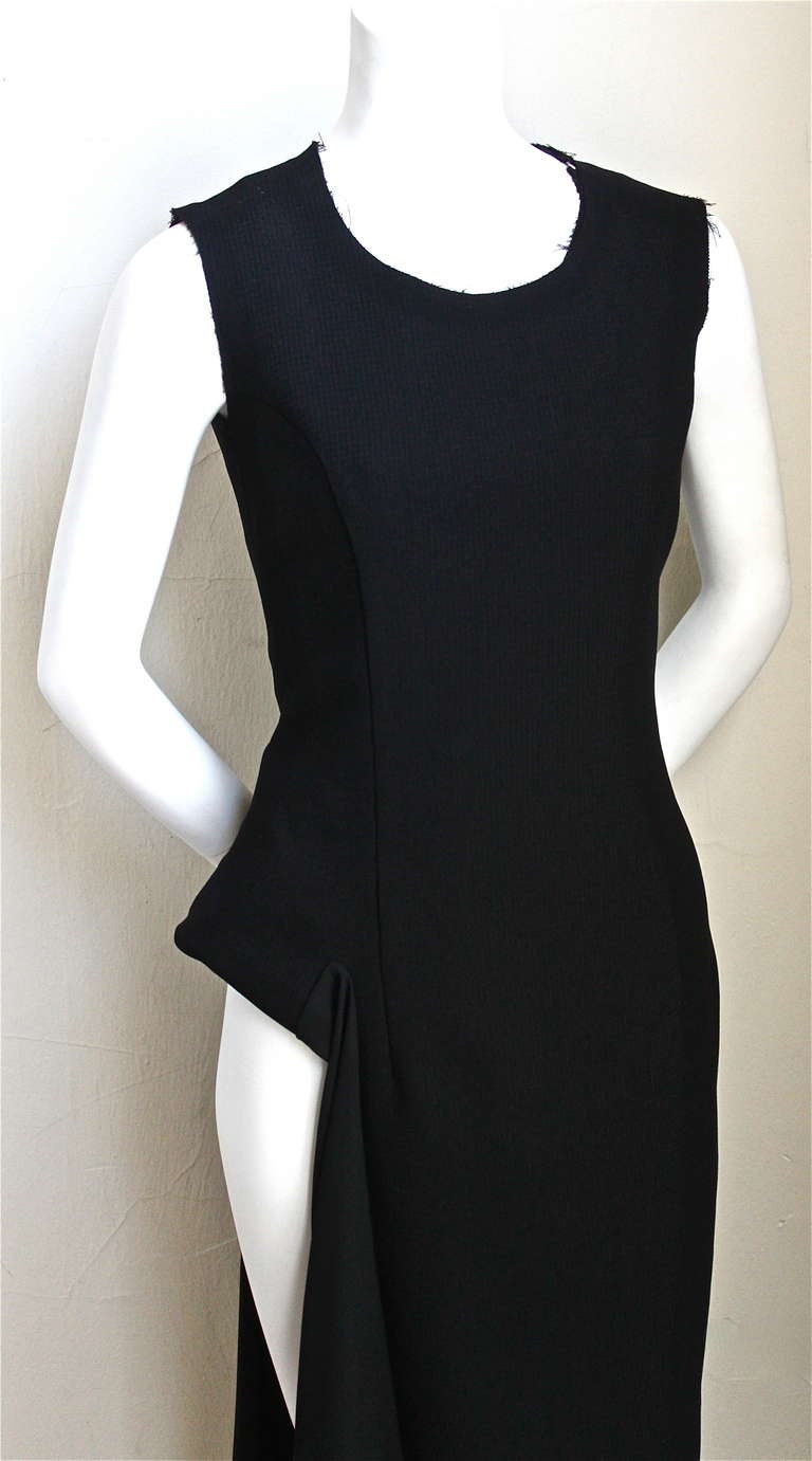 Jet black crepe double layer crepe dress with large cut out at side of right leg from Comme des Garcons dating to 1998. Raw edges to neckline and armholes. Inner layer of dress is a sheer chiffon fabric. Labeled a size S. Approximate measurements: