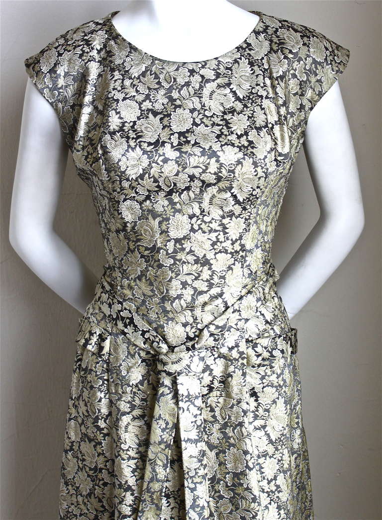 Very rare silver metallic brocade dress with cross tie detail at waist from Castillo for Jeanne Lanvin dating to the 1950's. Dress best fits a US 6-8. Approximate measurements: bust 35, waist 29.5