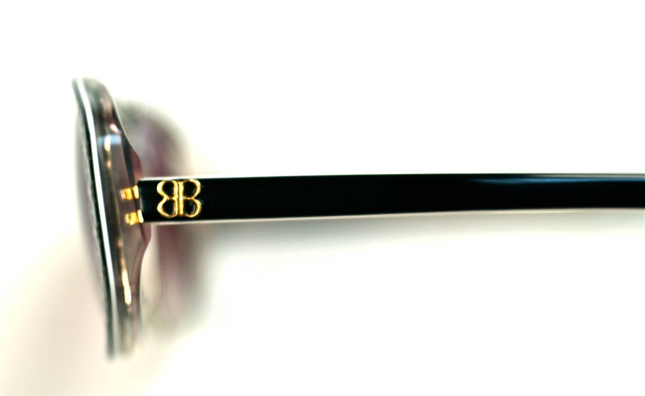 Unworn black plastic sunglasses with etched diagonal gold accents from Balenciaga dating to the 1980's. Measures approximately: 6