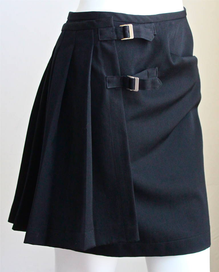 Very rare jet black asymmetrical wool skirt with pleating and double buckle closure from Comme des Garcons dating to fall of 1989. Labeled a size 'M'. Approximate measurements: Waist 27-28.5