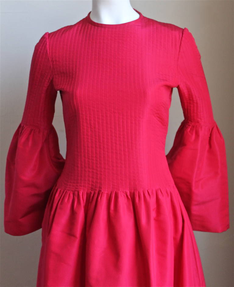 Vivid fuchsia taffeta gown with pleated bodice, bell sleeves and full skirt from Pierre Cardin dating to the 1960's. Fits a size 4. Approximate measurements are: shoulders 14