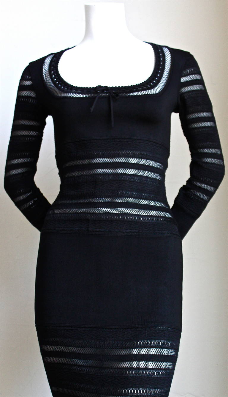 Very rare jet black long dress with open lace knit panels, flounced cuffs and adjustable neckline from Azzedine Alaia dating to 1993. Labeled a size 'm' however this dress runs small. Approximate measurements: shoulders 14