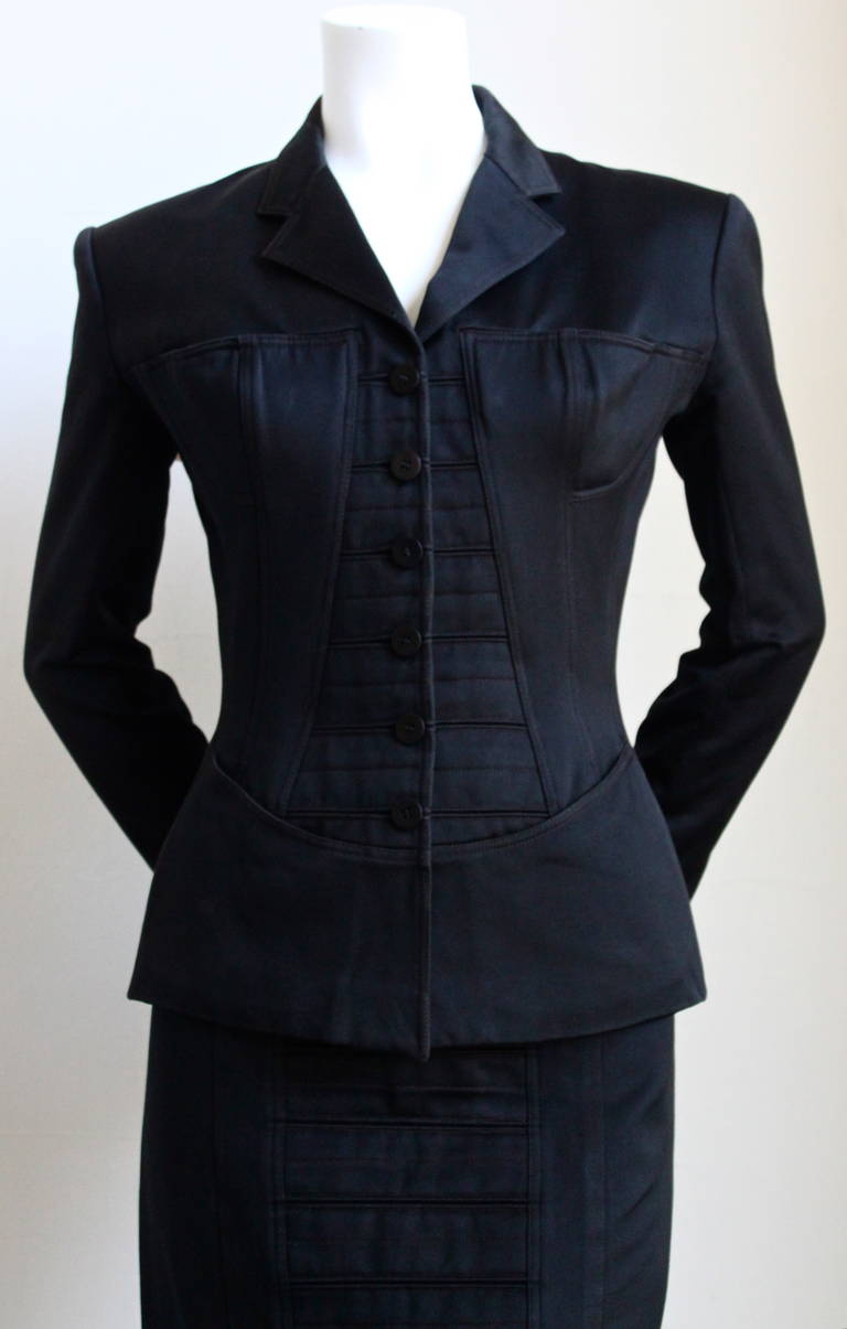 Striking black seamed skirt suit from Alaia dating to spring of 1992. Corseted jacket with uniquely placed breast pockets. Incredibly flattering fit. Jacket is a FR 40 and skirt is a FR 38. Fits a US 2 or 4. Jacket measures 35