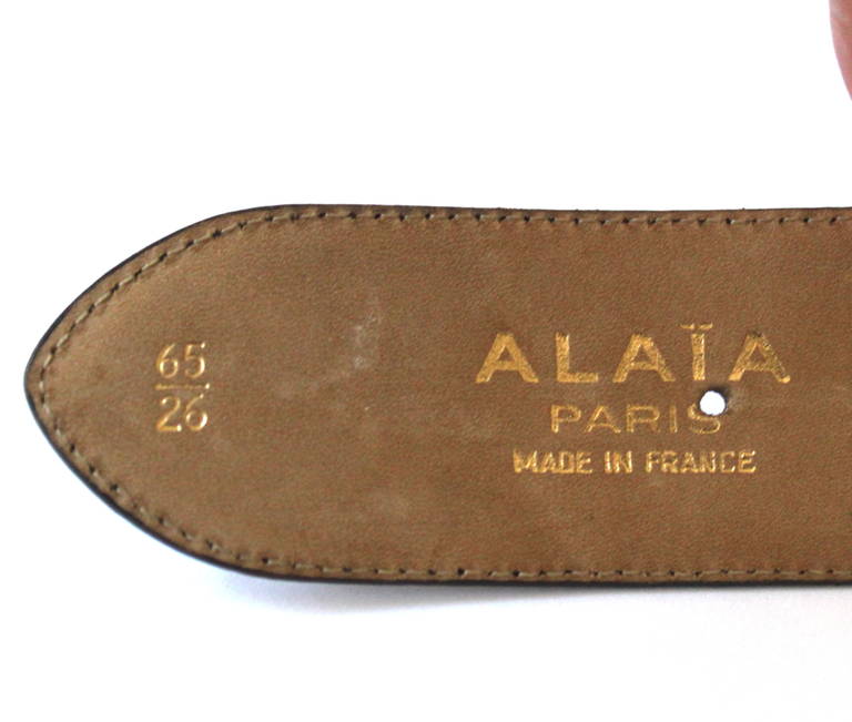 Brown leather woven belt with antiqued brass buckle from Azzedine Alaia dating to the late 1980's. Labeled a French size 65 or XS. Holes fall at 24