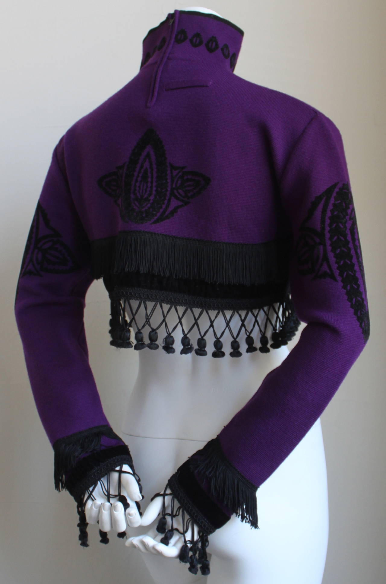 Very rare cropped purple wool sweater with black flocked pattern, fringe and tassels from Jean Paul Gaultier for Equator dating to the early 1980's. Fits a size 2-6. Approximate measurements (unstretched): shoulder 16