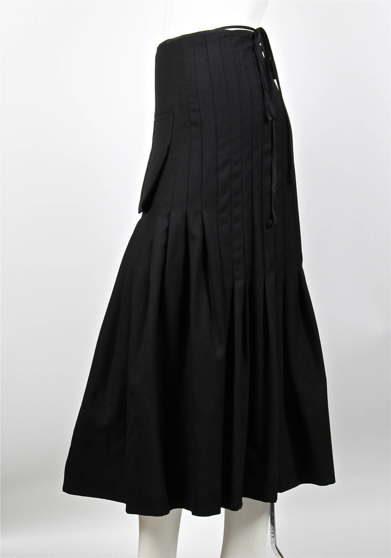 Jet black pleated wool wrap skirt with front pocket from Yohji Yamamoto. Size 1. Approximate measurements: waist 30