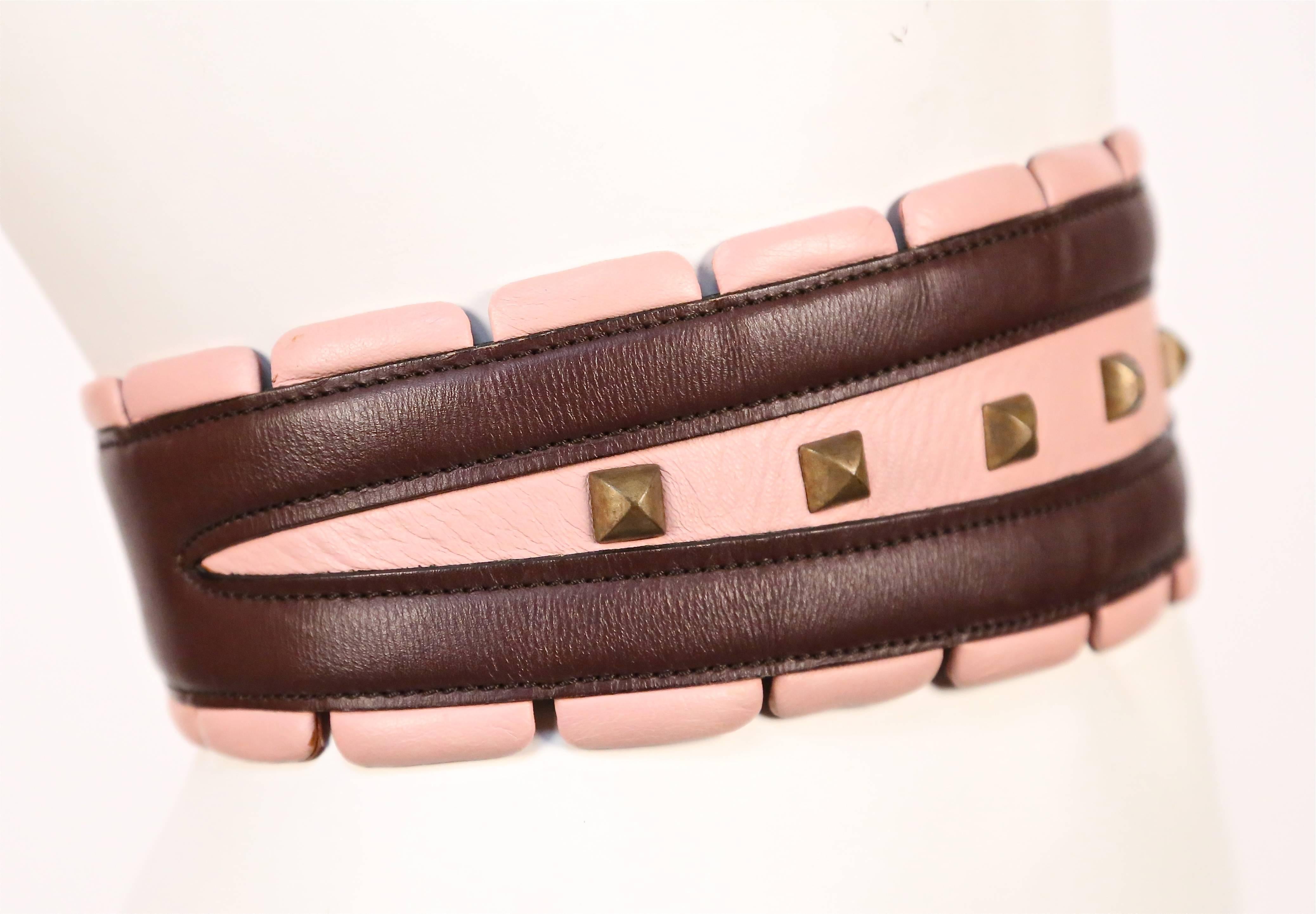 Very rare burgundy and pink leather belt with brass toned pyramid studs from Azzedine Alaia dating to the early 1990's. Belt is labeled a French 65 and ideally fits a 23-25