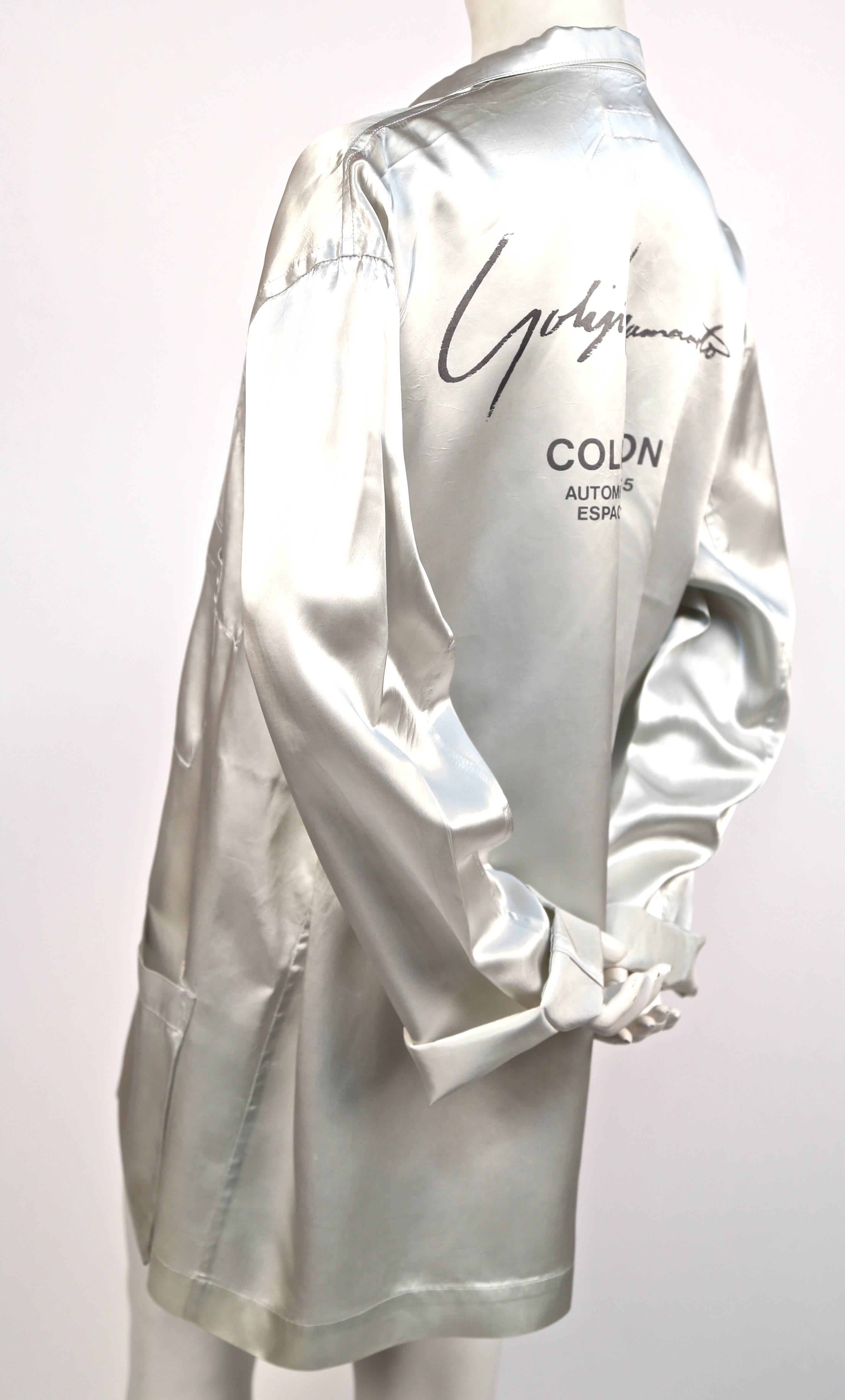 Very rare silver satin staff jacket with multiple pockets from the Yohji Yamamoto fall 1984 runway show.  Jacket printed 'Yohji Yamamoto Collection Automne Hiver '84-85 Espace 5, Shinjuku'. These jackets were given to those working backstage so they