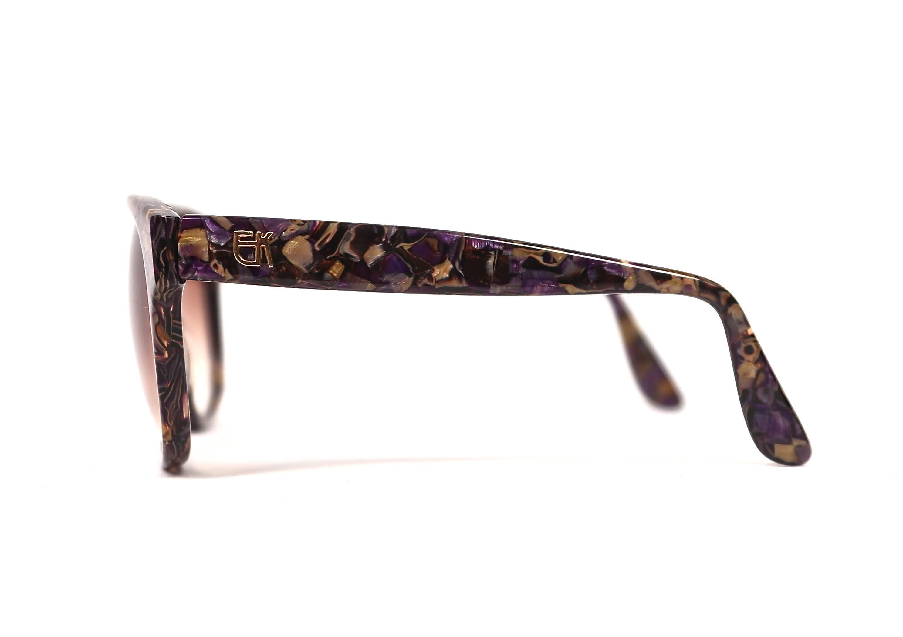 Vivid purple and gold mosaic sunglasses with gilt EK logo at temples from Emmanuelle Khanh dating to the late 1970's. Oversized frames are great fort a medium or larger sized face. Approximate measurements: 155 mm from temple to temple, 58 mm from