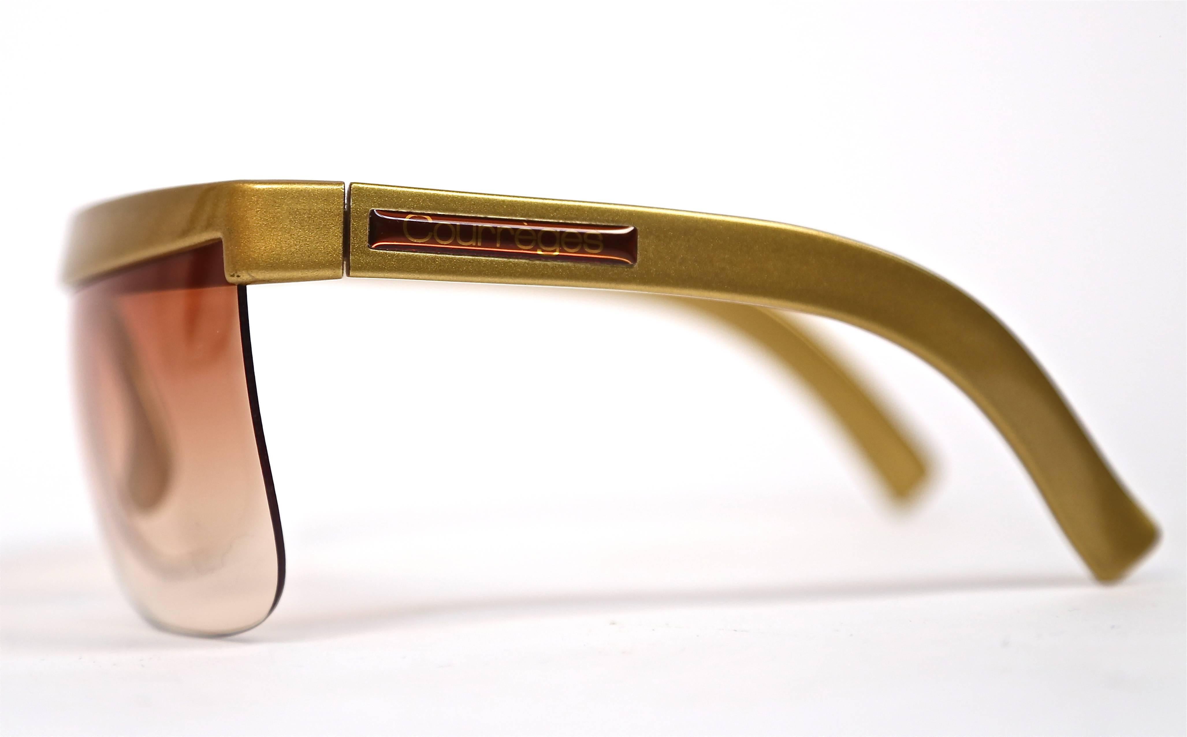 Very unusual futuristic gold plastic shield sunglasses from Courreges dating to the 1970's. Sunglasses measure approximately 6" across and 2.33" from top to bottom. Made in France. Very good condition.  Come with original pouch.