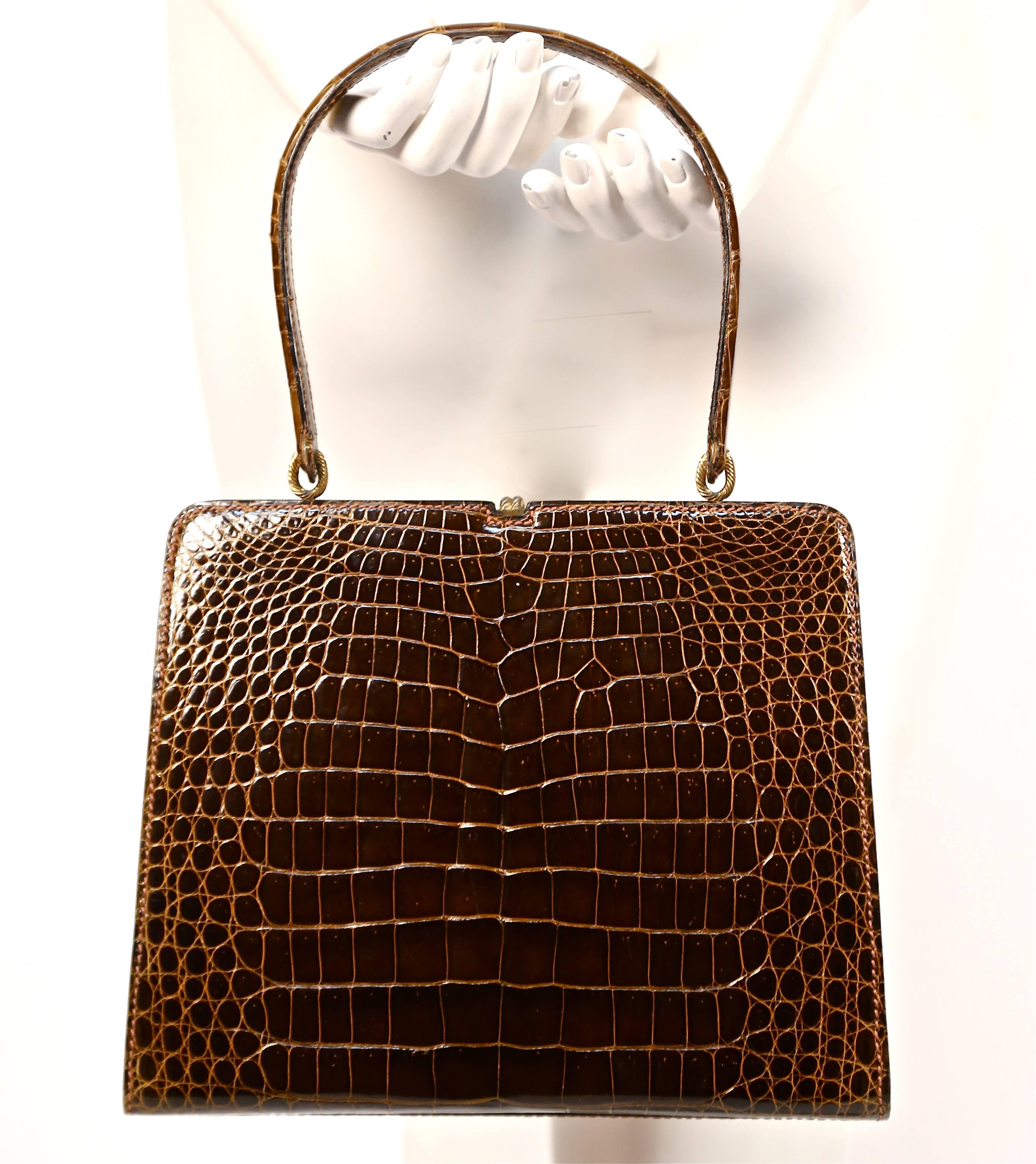 Very rare brown crocodile leather top handle bag with beautiful gilt hardware designed by Loewe dating to the 1960's. Approximate measurements: width at top 8.5