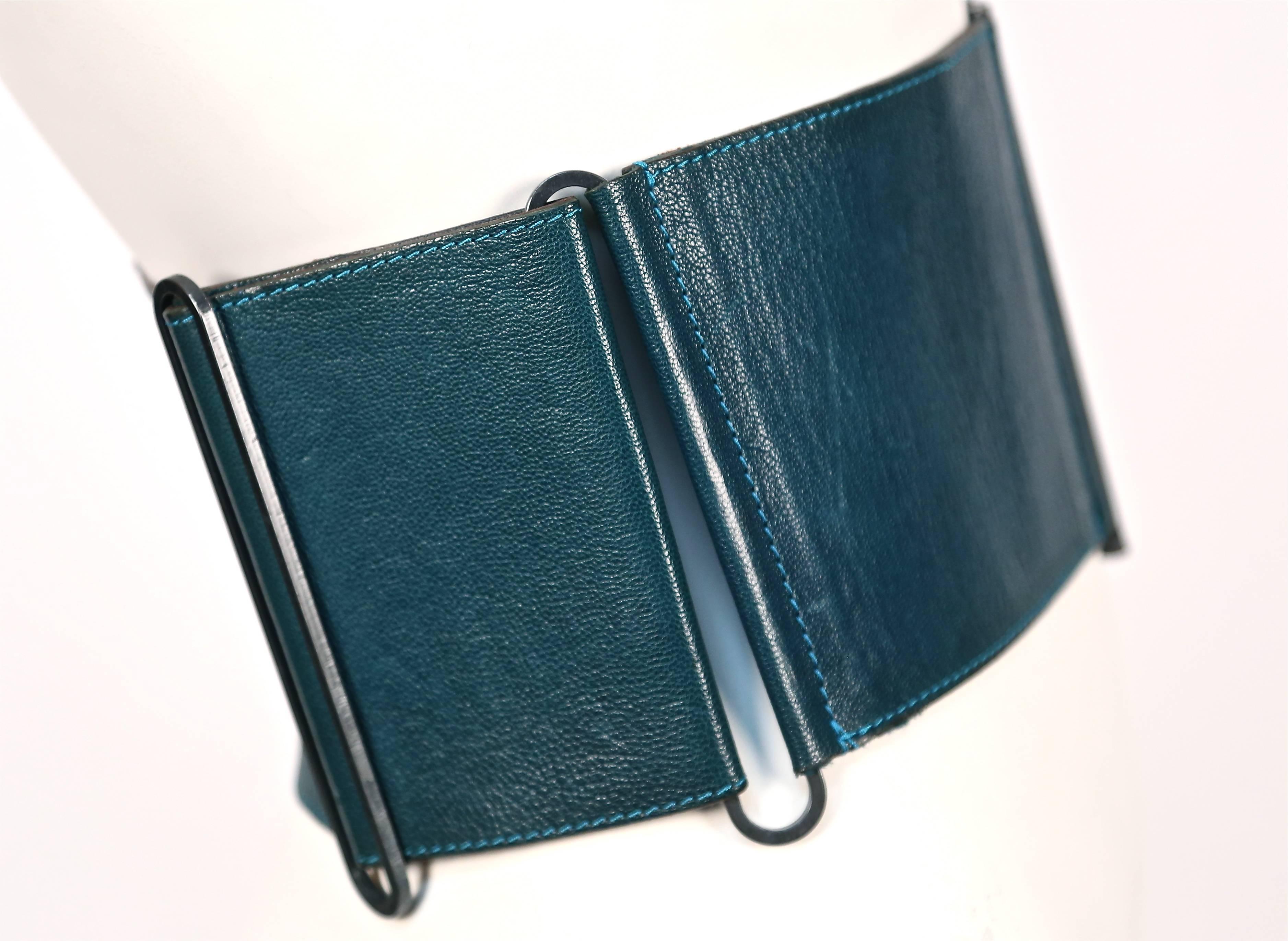 Vivid teal leather belt by Lanvin designed by Claude Montana dating to the early 1990's.  Very interesting fastening consisting of a long thin metal rod that slides into a metal tube casing on the opposing side. Best suited for a size S/M. Measures