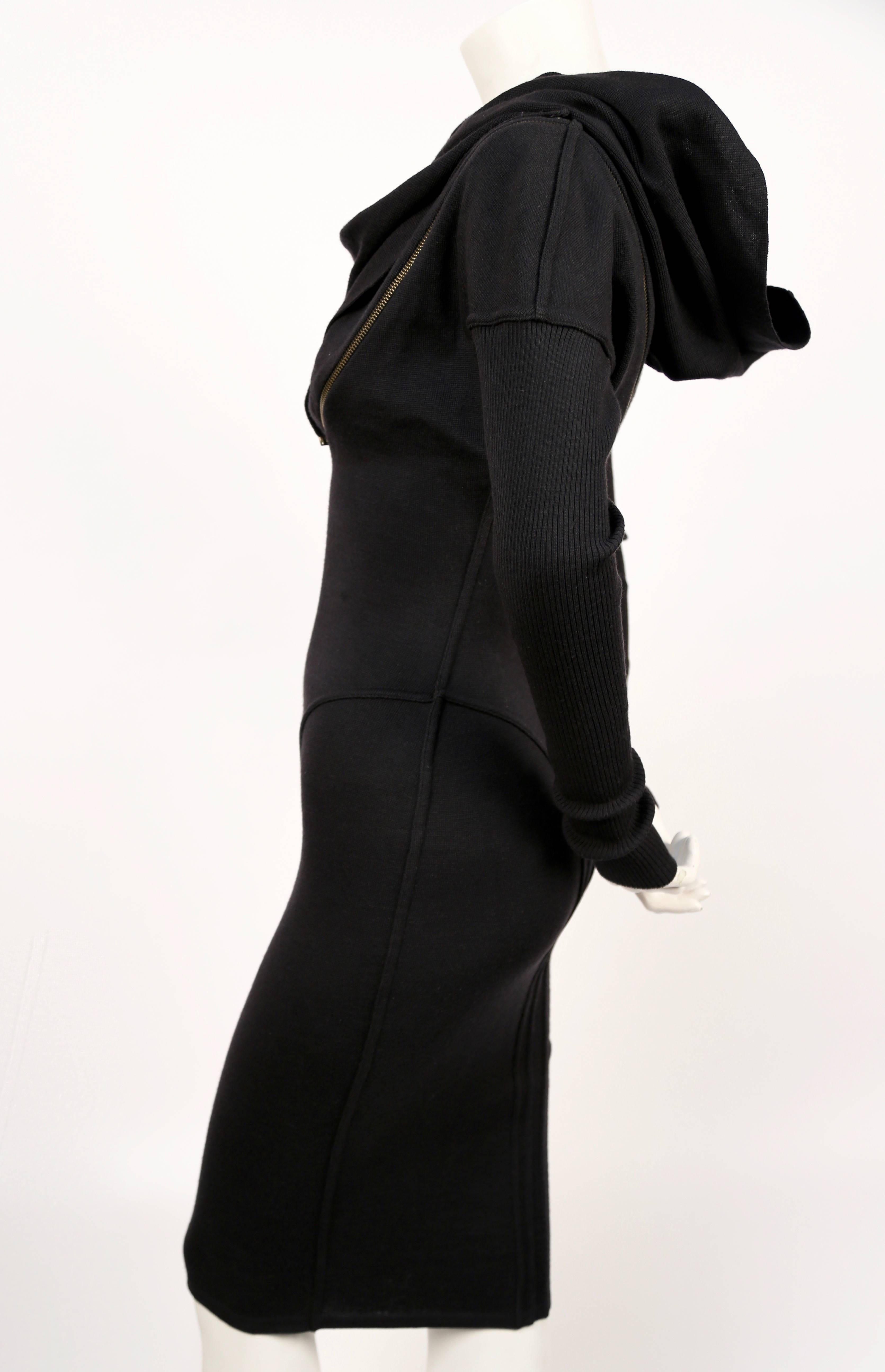 Iconic black wool seamed zipper dress with hood designed by Azzedine Alaia dating to fall of 1986. Well documented piece. Very flattering seams with spiral zipper that cleverly follows the contours of dress seams. 'Hood' can be draped for a more