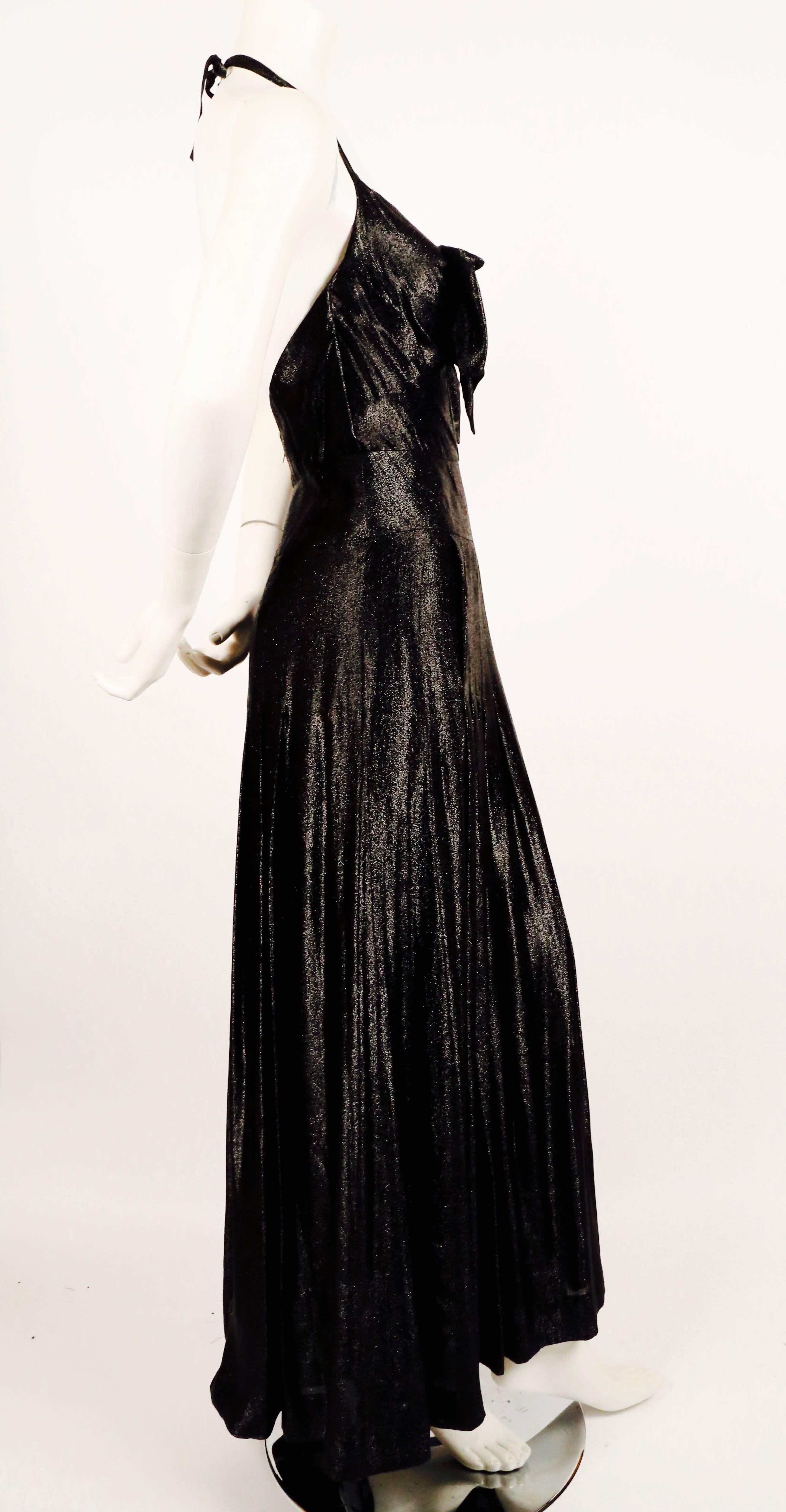 Metallic black silk floor length gown with pleated skirt and bow detail from Chanel dating to 1983 which was Karl Lagerfeld's first year at Chanel. Dress is labeled a French size 40 however it best fits a modern US 4 or 6. Approximate measurements: