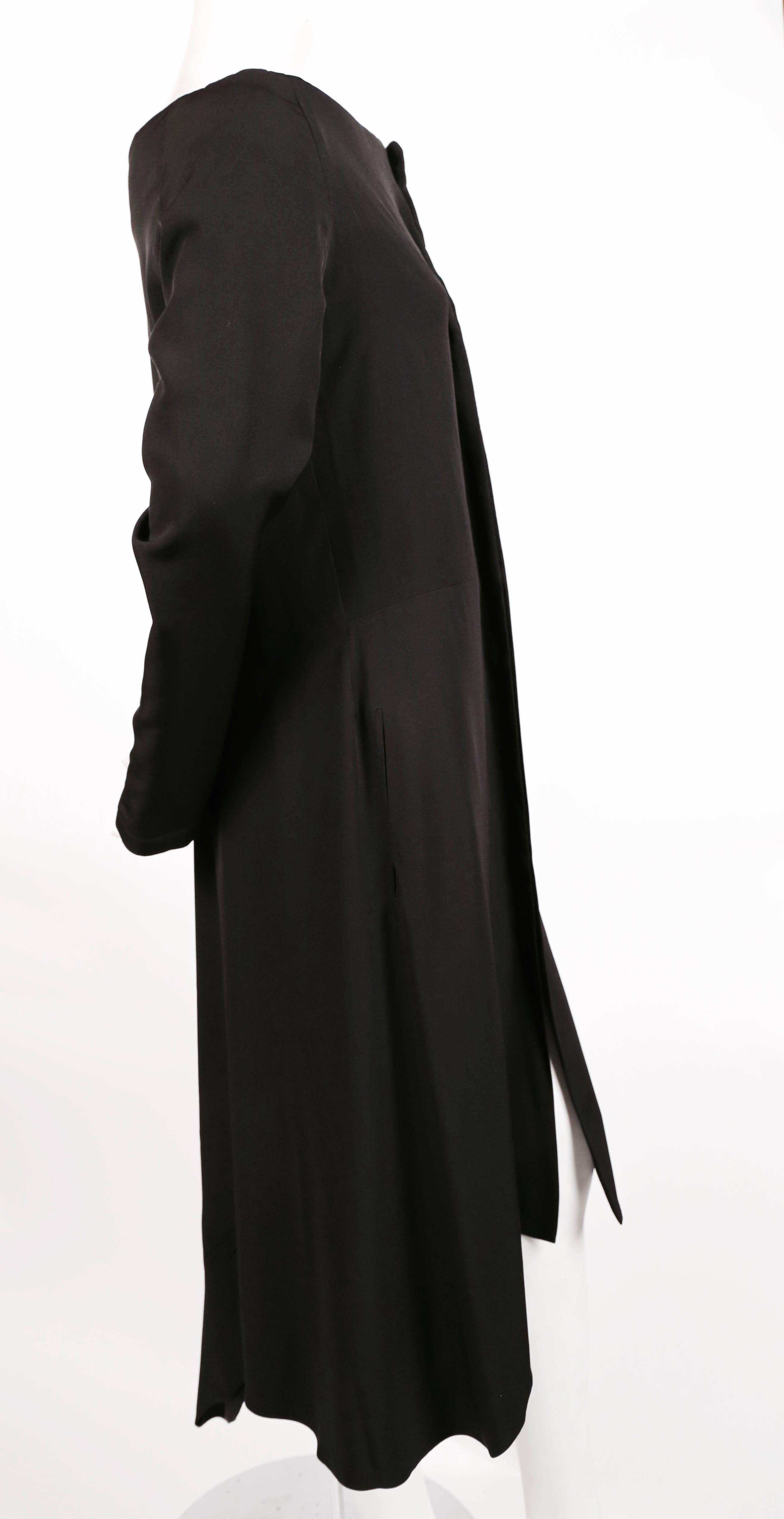 Very unusual, jet-black, lightly padded silk and wool dress with snap closure, asymmetrical hemline and exaggerated raised collar from Yohji Yamamoto dating to the 1990's. Size 2. Dress has a loose graceful fit through the body. Approximate