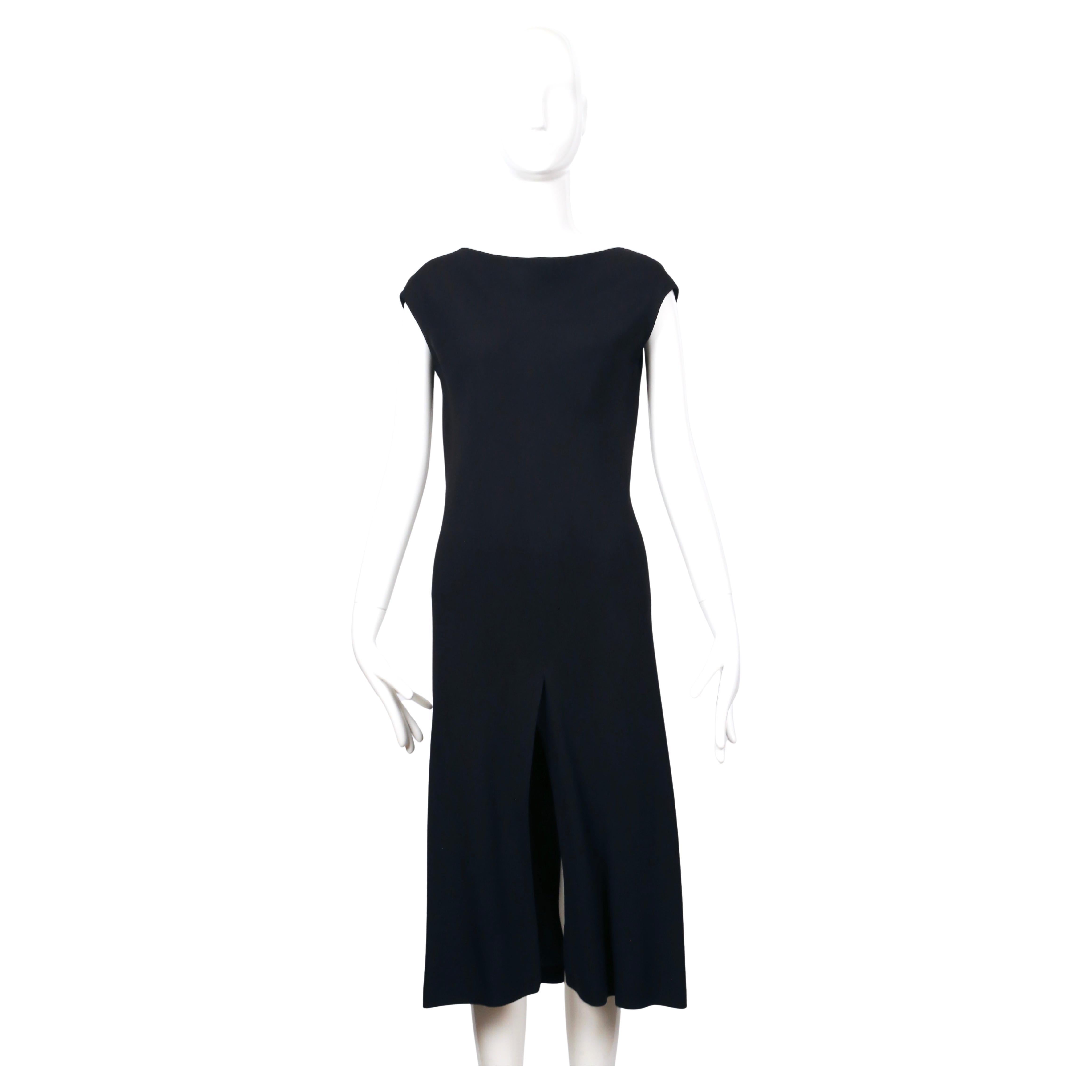 Si tratta di un abito nero minimalista ma di grande effetto, disegnato da Halston negli anni '70. Realizzato in un tessuto crepe fluido, l'abito è tagliato in sbieco con cuciture a spirale che lo fanno scivolare sul corpo. La silhouette è pulita e