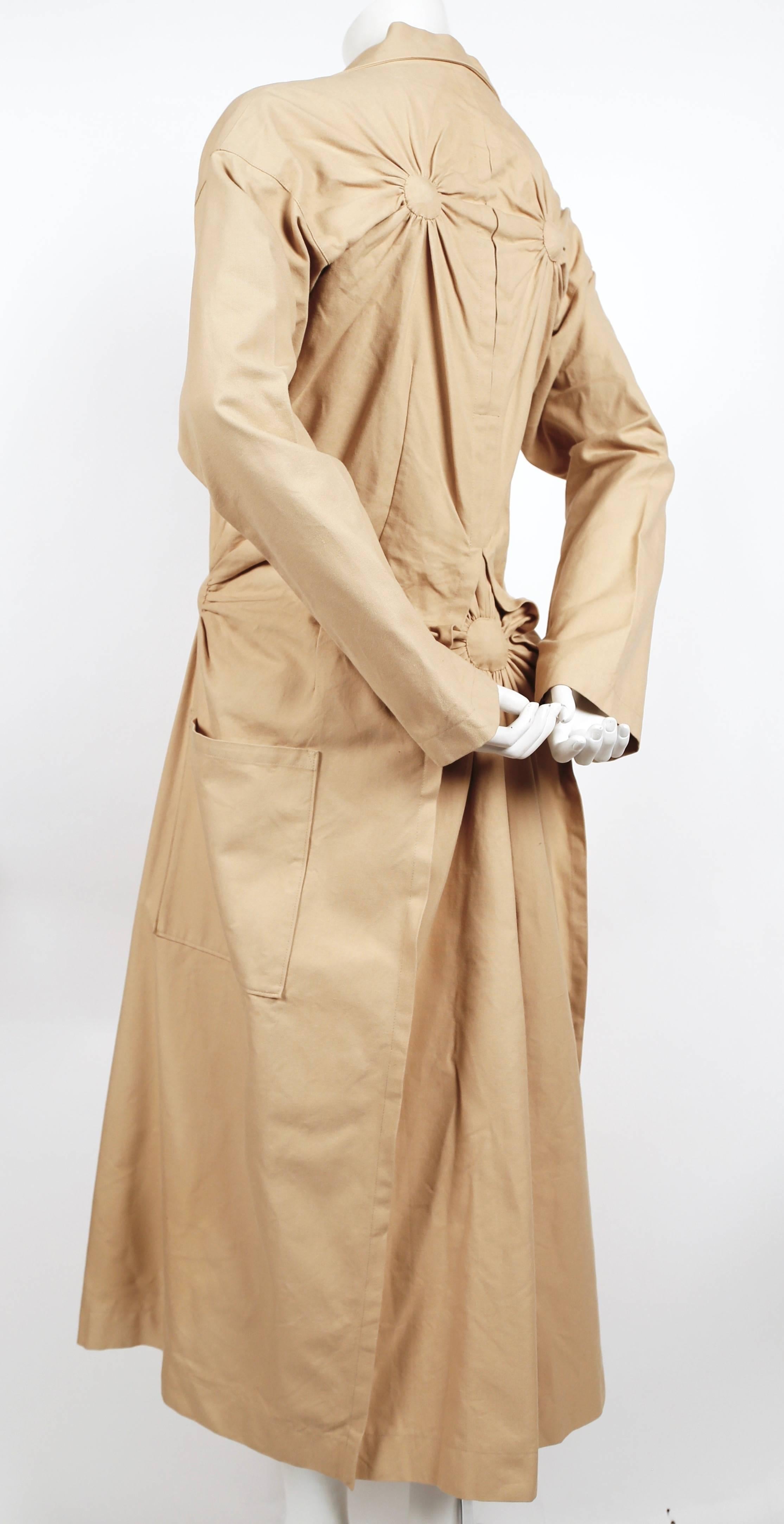 Tan cotton trench with unique ruching, bustle back and plaid lining designed by Issey Miyake dating to fall of 2003 exactly as seen on the runway. Japanese size 2. Approximate measurements: waist 30