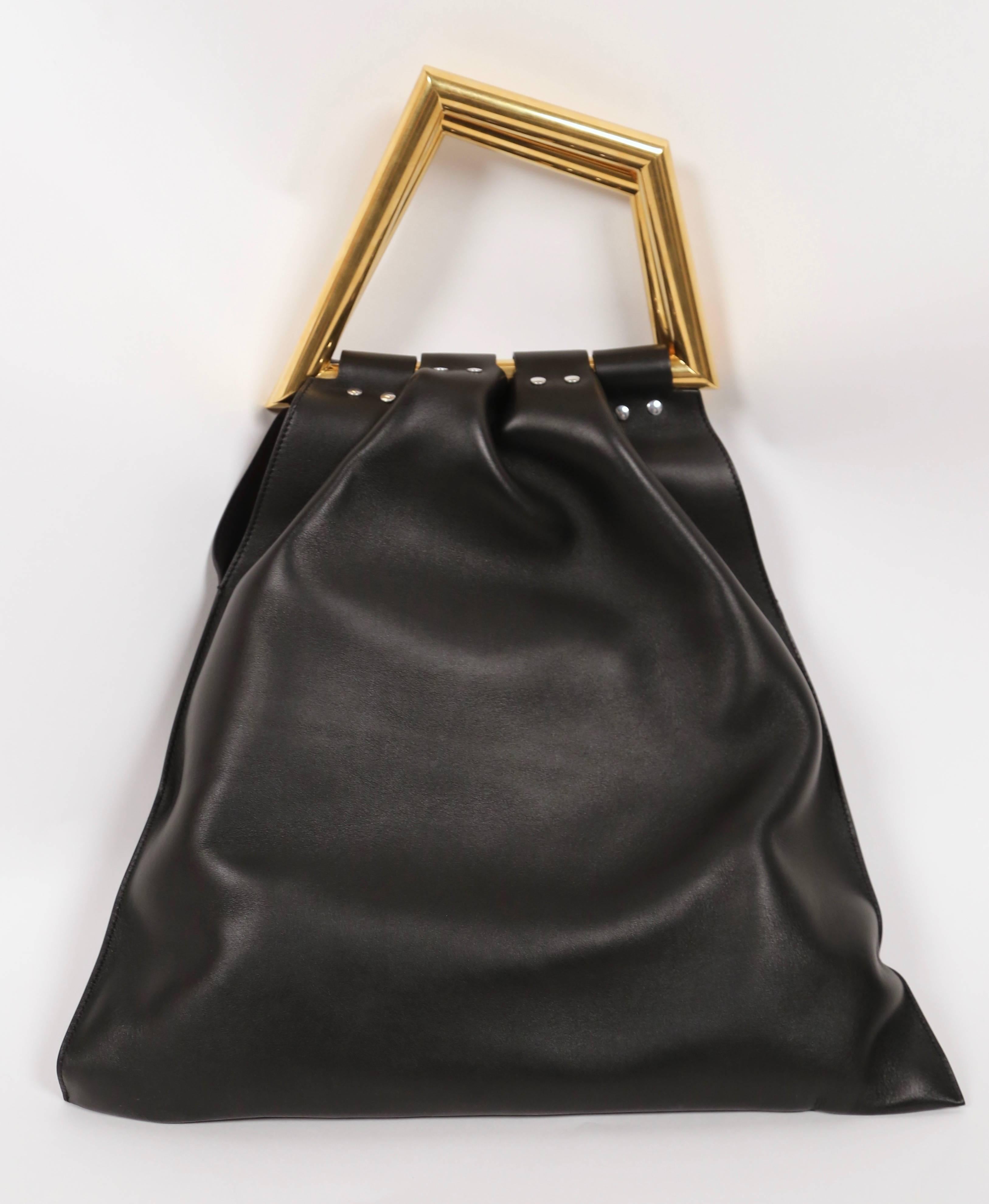 Black leather 'TRIANGLE HANDLE BAG' designed by Phoebe Philo for Celine dating to spring of 2014 exactly as seen on the runway. Color is all black leather with brass/gold metal handle and silver grommets. There are two gold-toned metal top handles,