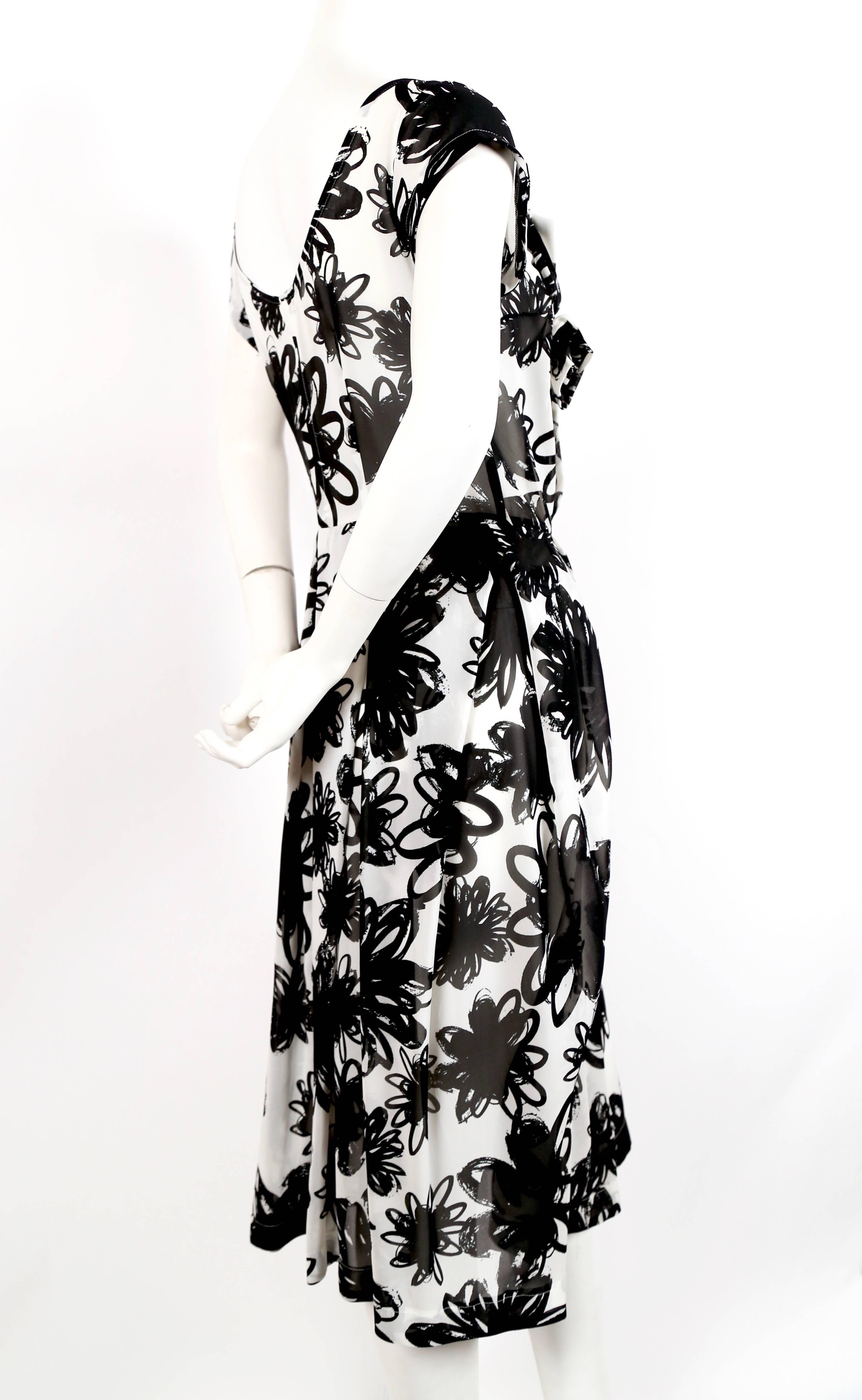 Black and white abstract floral dress with asymmetrically draped neckline and 'flower' accent from Comme Des Garcons. Size 'S'. Approximate measurements: shoulder 15", bust 35", waist 32" and length 46". Fabric is very