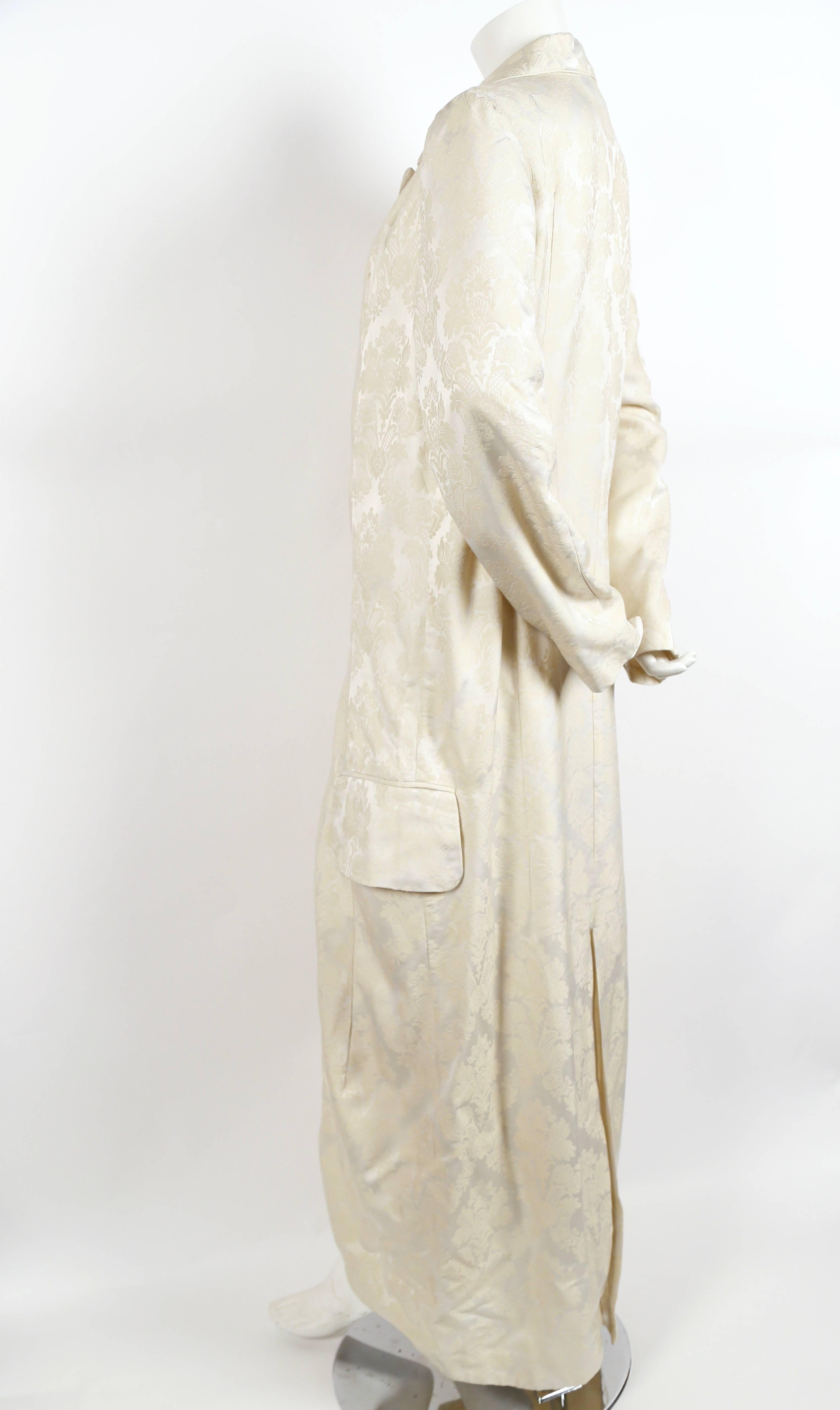 Exaggeratedly long cream brocade coat designed by Rei Kawakubo dating to spring of 1993. Size M. Approximate measurements: shoulder 17", bust 42", waist 39", hips 42", arm length 25.5" and overall length 59". Button