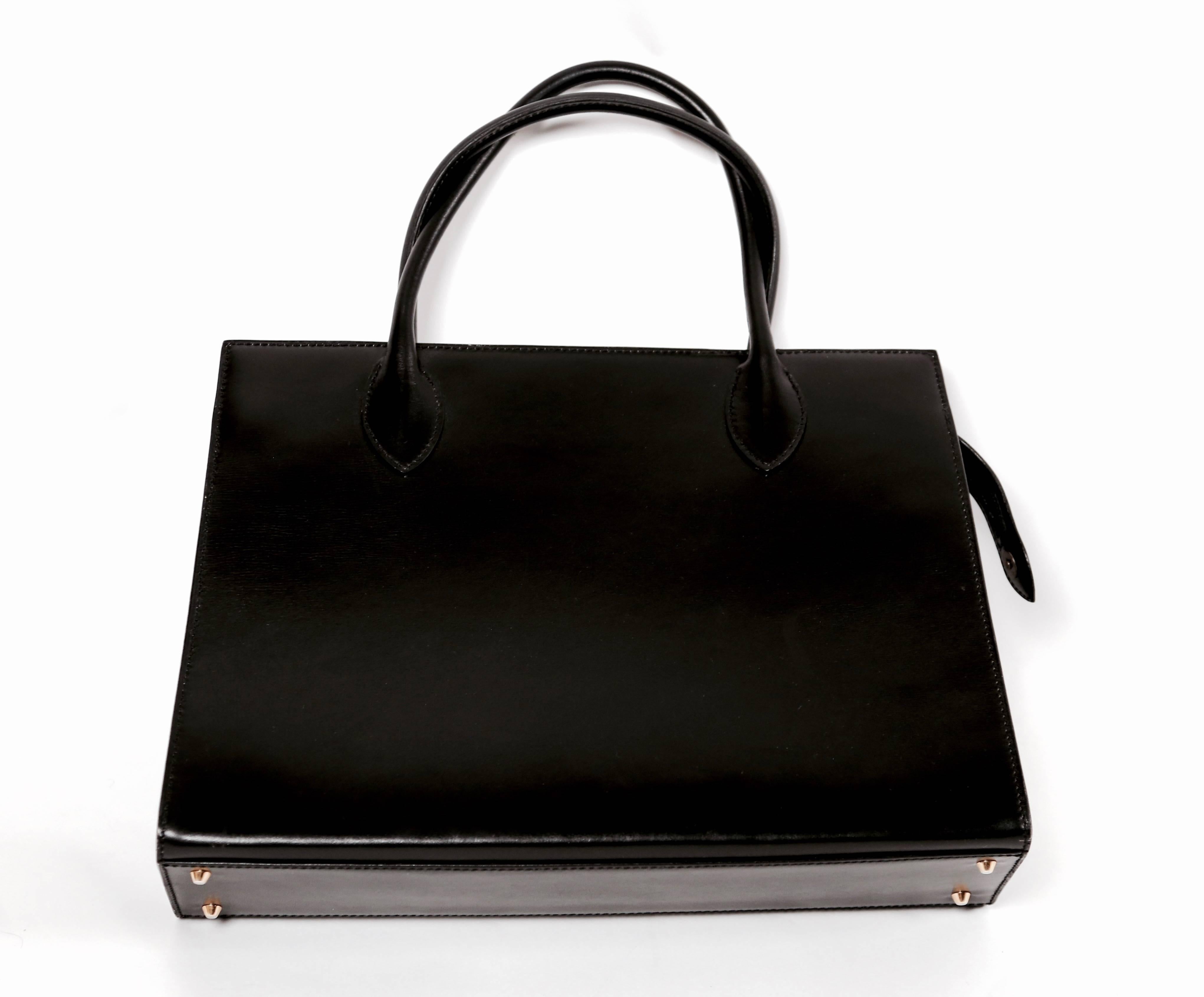 Minimal, jet-black leather box bag designed by Azzedine Alaia dating to the 1980's. Approximate measurements: base measures just under 13" wide, width at top 12" wide, height 9.25" tall and depth 3.75". Strap drop is