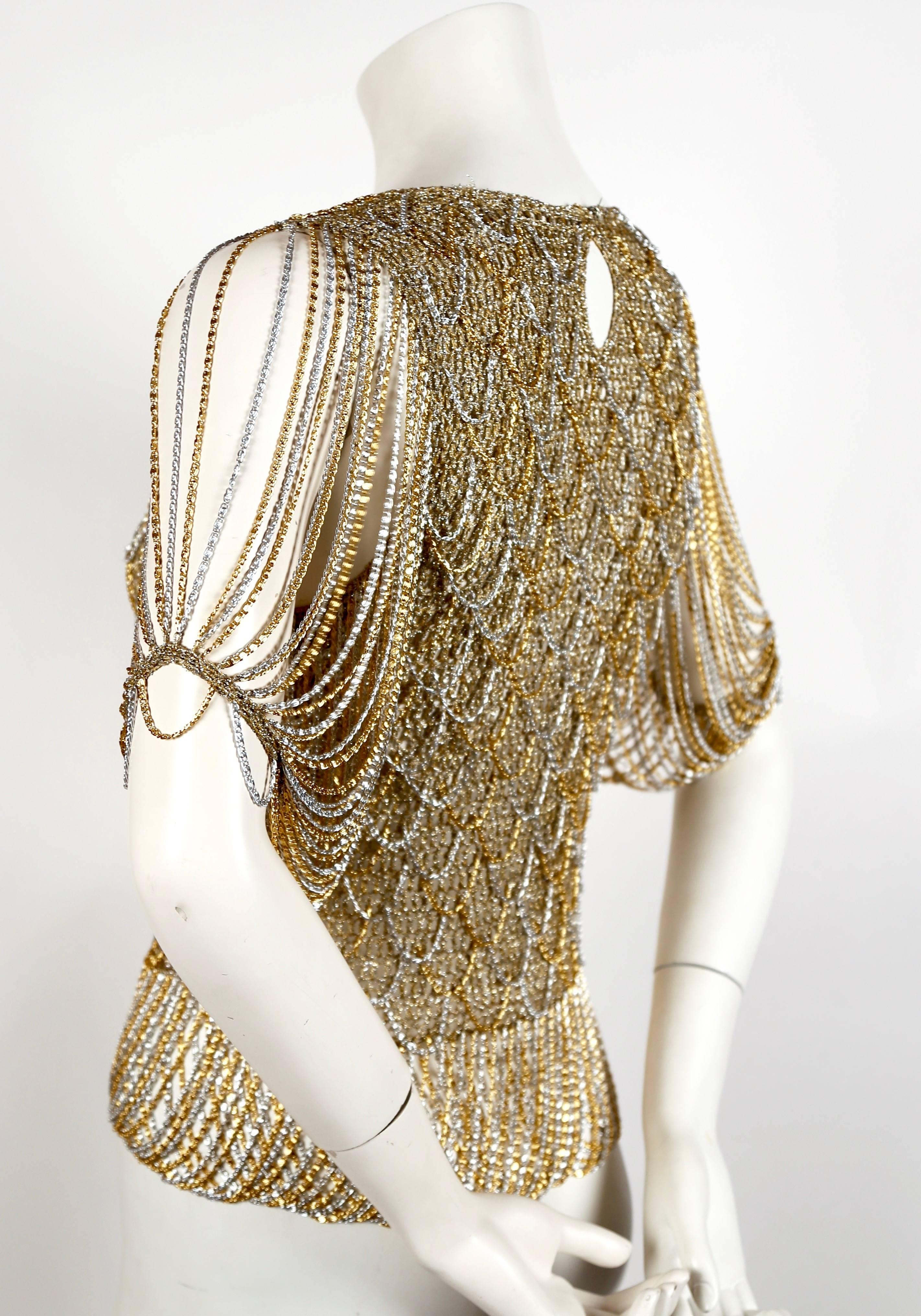 Intricately woven gold and silver metallic sweater intertwined with chain from Loris Azzaro dating to the 1973. Same style sweater as seen in Helmut Newton photograph. Fits a size XS or S. Approximate measurements (unstretched): 26" at bust and