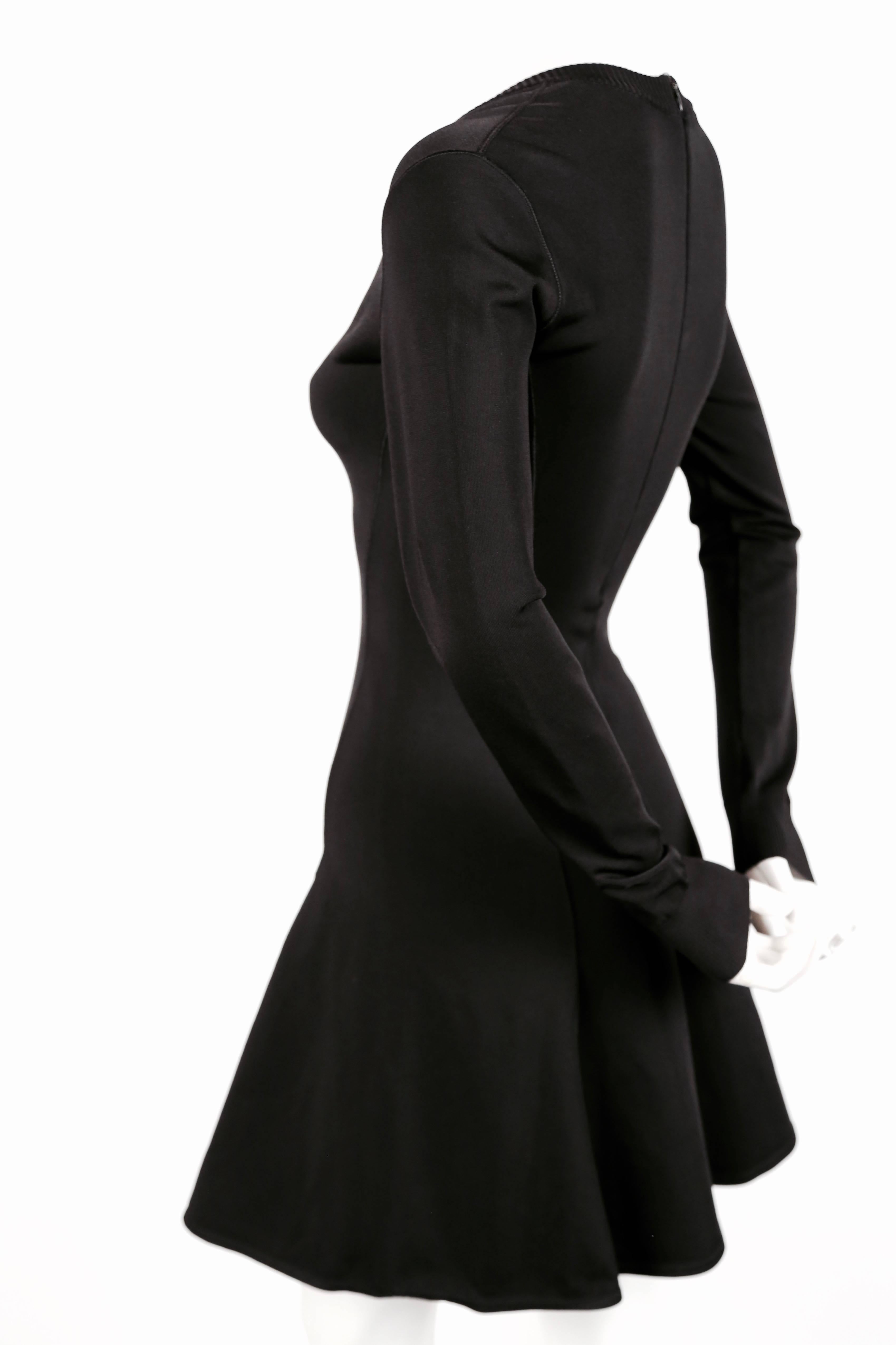 Jet black skater dress with V-neckline and long sleeves designed by Azzedine Alaia dating to the early 1990's. Size XS. Approximate measurements (unstretched): shoulder 14
