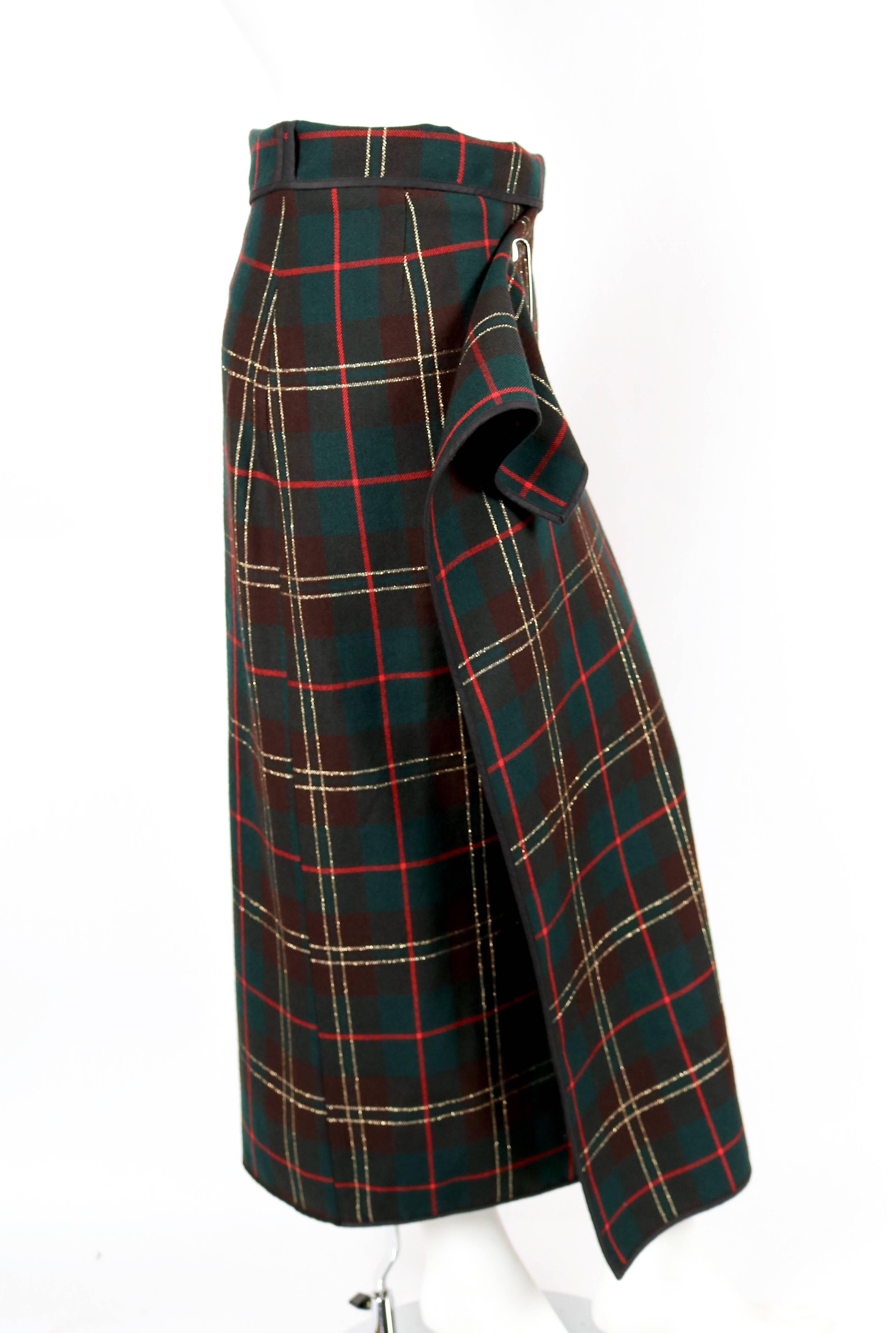 Tartan wool wrap skirt accented with lurex and secured with a safety pin designed by Rei Kawakubo for Comme Des Garcons dating to fall of 1999. No size label. Skirt is a rectangle measuring 52.5