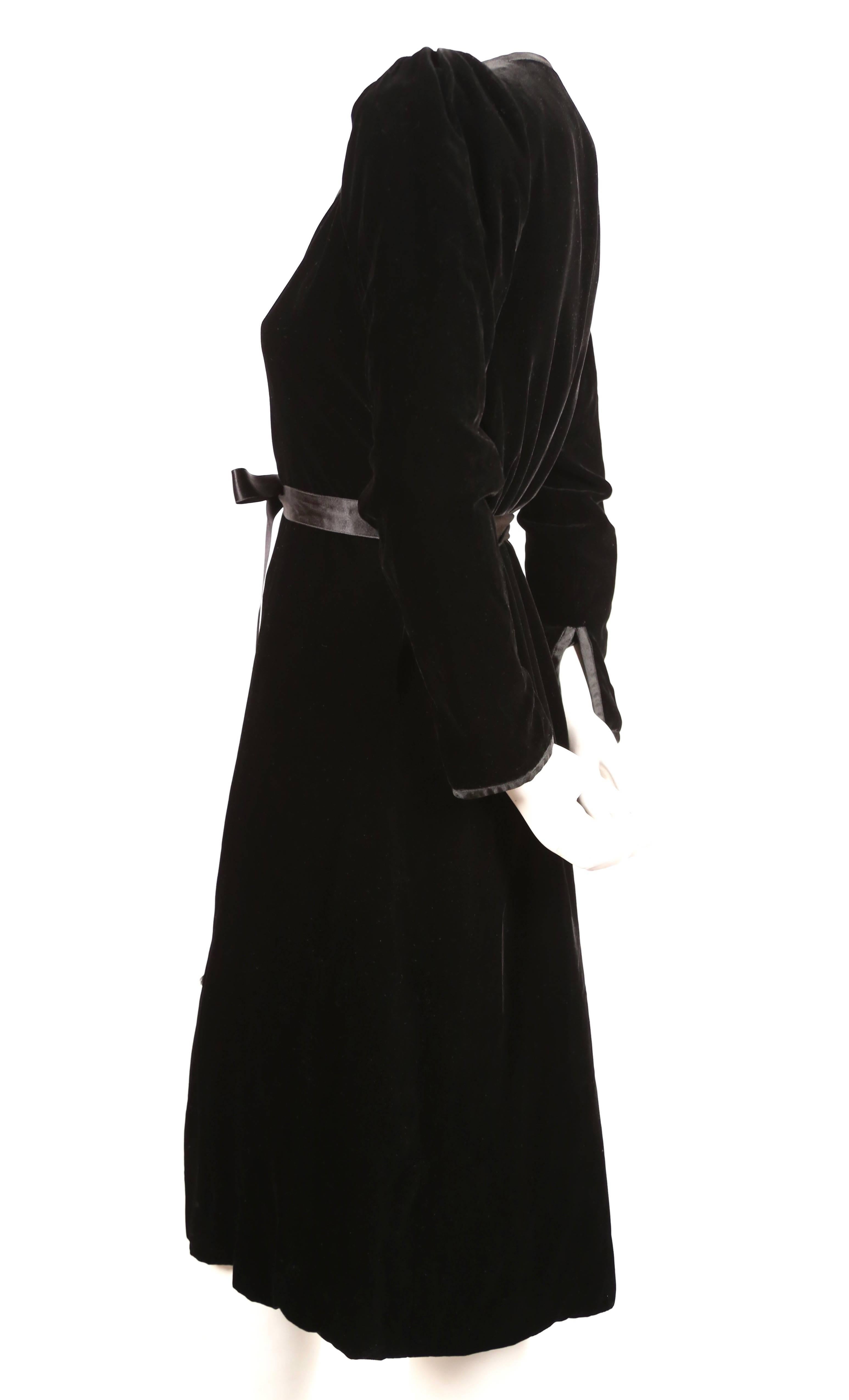 Jet black velvet wrap dress with satin ribbon trim designed by Yves Saint Laurent dating to the 1970's. Labeled a French size 36. Approximate measurements: shoulders 14