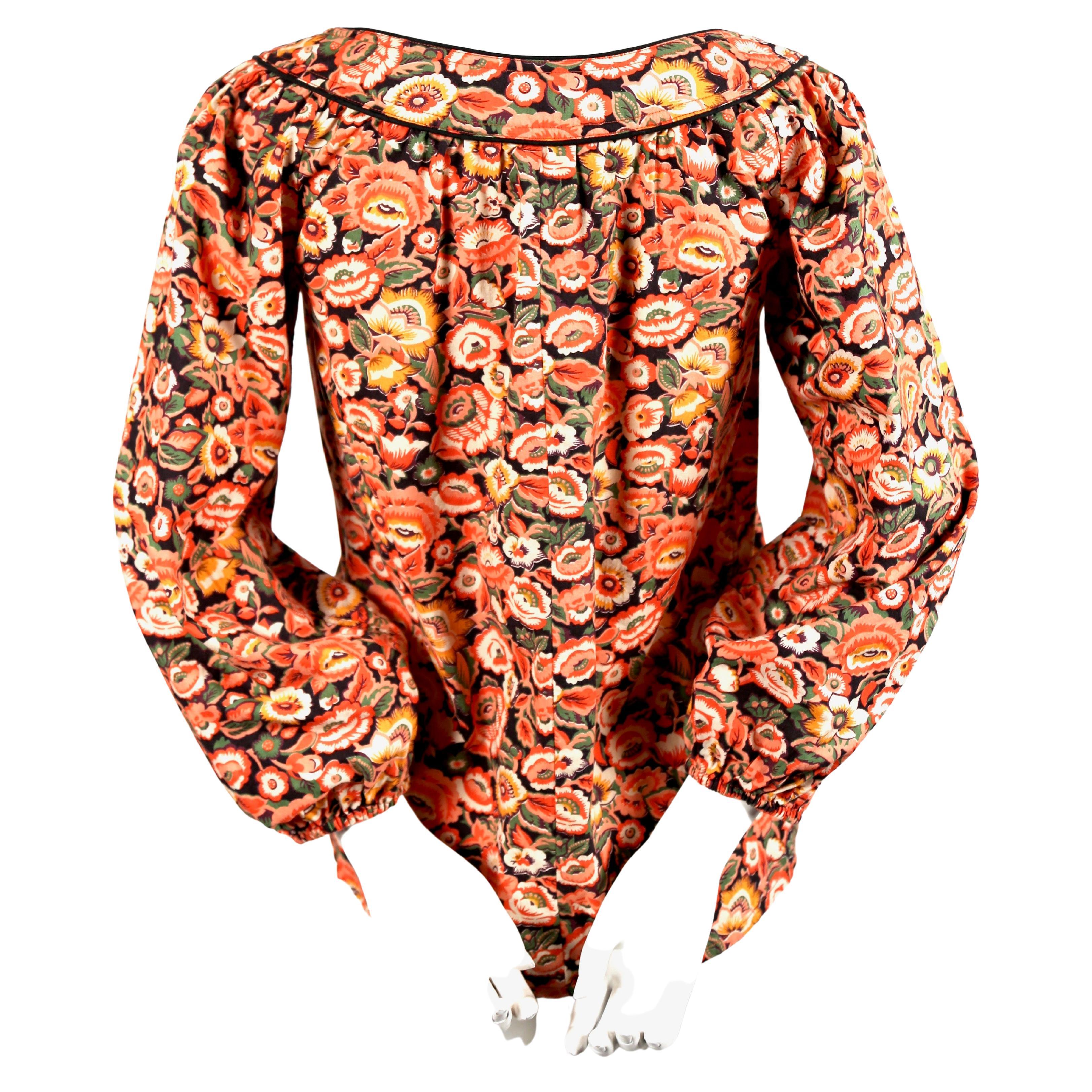Vivid, floral-printed, cotton peasant shirt with black piping and elasticized cuffs designed by Yves Saint Laurent dating to the 1970's.  French size 34. Fits a size 2 or 4. Approximate measurements: shoulder 14-14.5