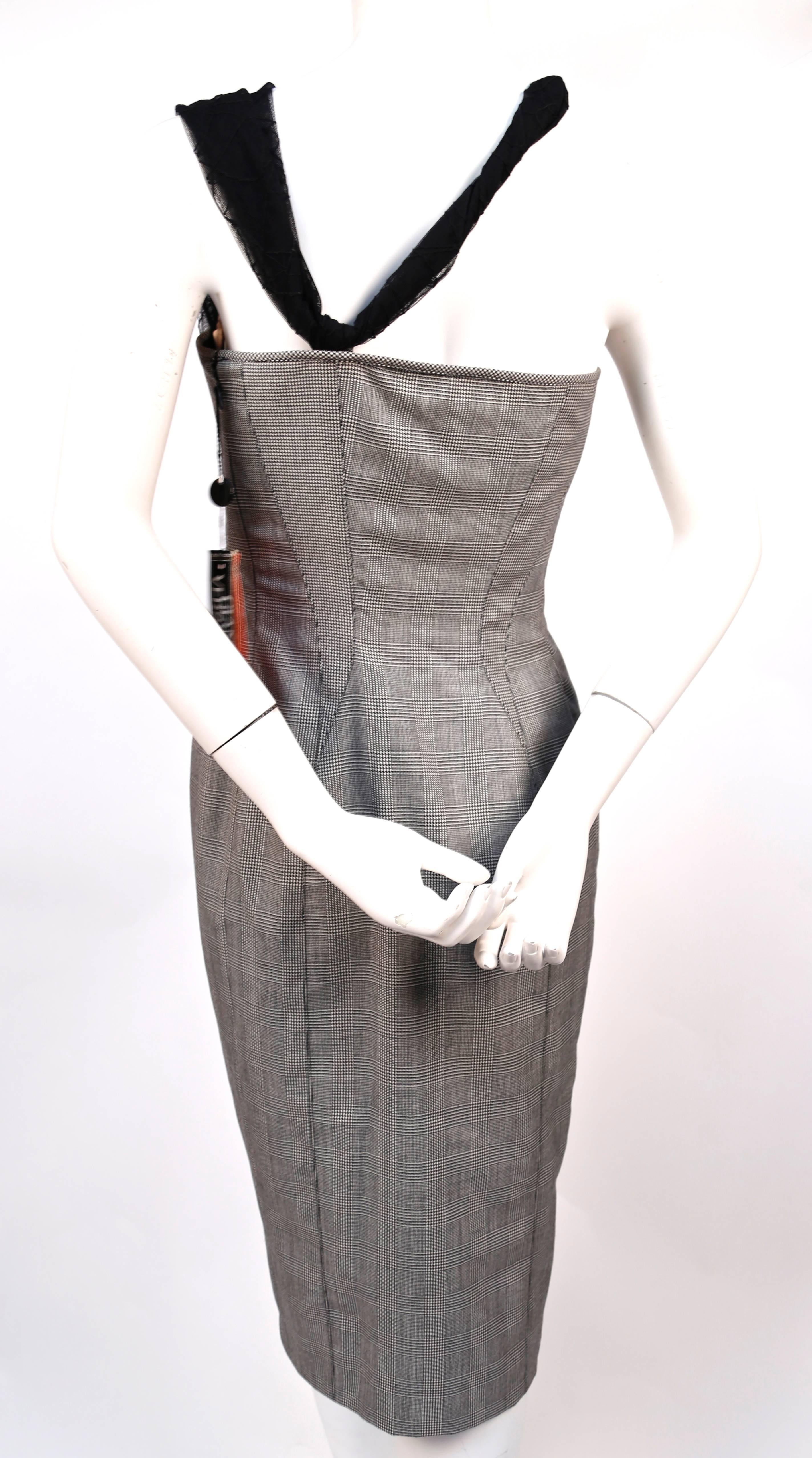 Black and white houndstooth dress with asymmetrical mesh bustier designed by Gianni Versace dating to 1998. Similar version seen on Naomi Campbell on the runway. Italian size 42. Approximate measurements: bust 33