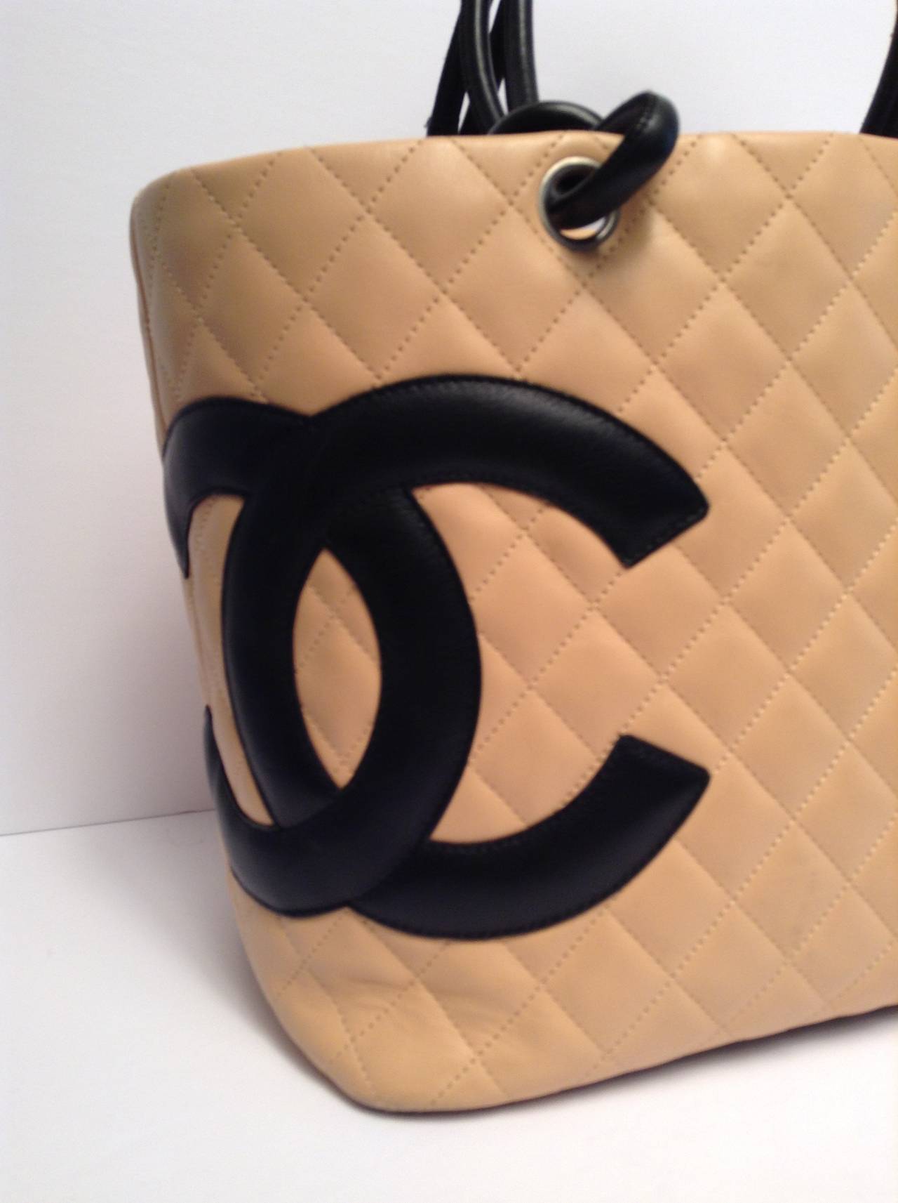 This is a chic and stylish bag from the Chanel Ligne Cambon collection and is very popular among Chanel lovers everywhere. The beige quilted leather features a bold black leather CC logo and silver hardware. The interior is roomy with black lining