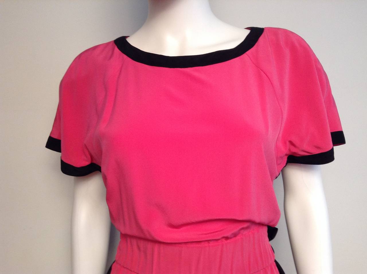 An amazing vintage number by none other than Karl Lagerfald. The black and pink short sleeve dress features small snap in shoulder pads, small peekaboo at under arm and a wide elasticized waist and side pockets. The waist is finished with an