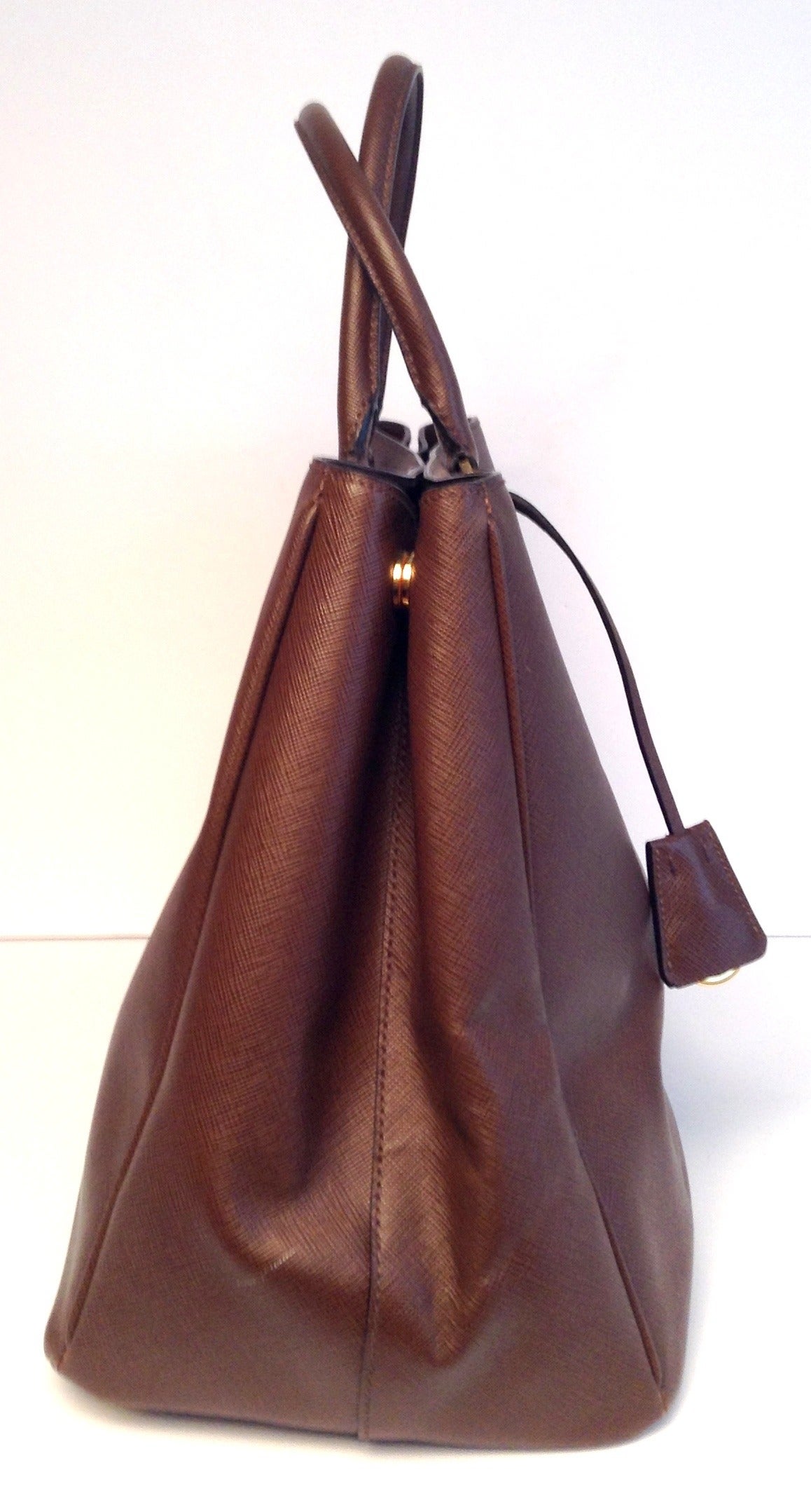This is an authentic PRADA Saffiano Lux Tote in Cacao Cocoa Brown. This tote is crafted of luxurious Prada Saffiano cross-crain leather in a classic structure. The base has brass feet for sturdiness. The bag has leather piping along the borders and