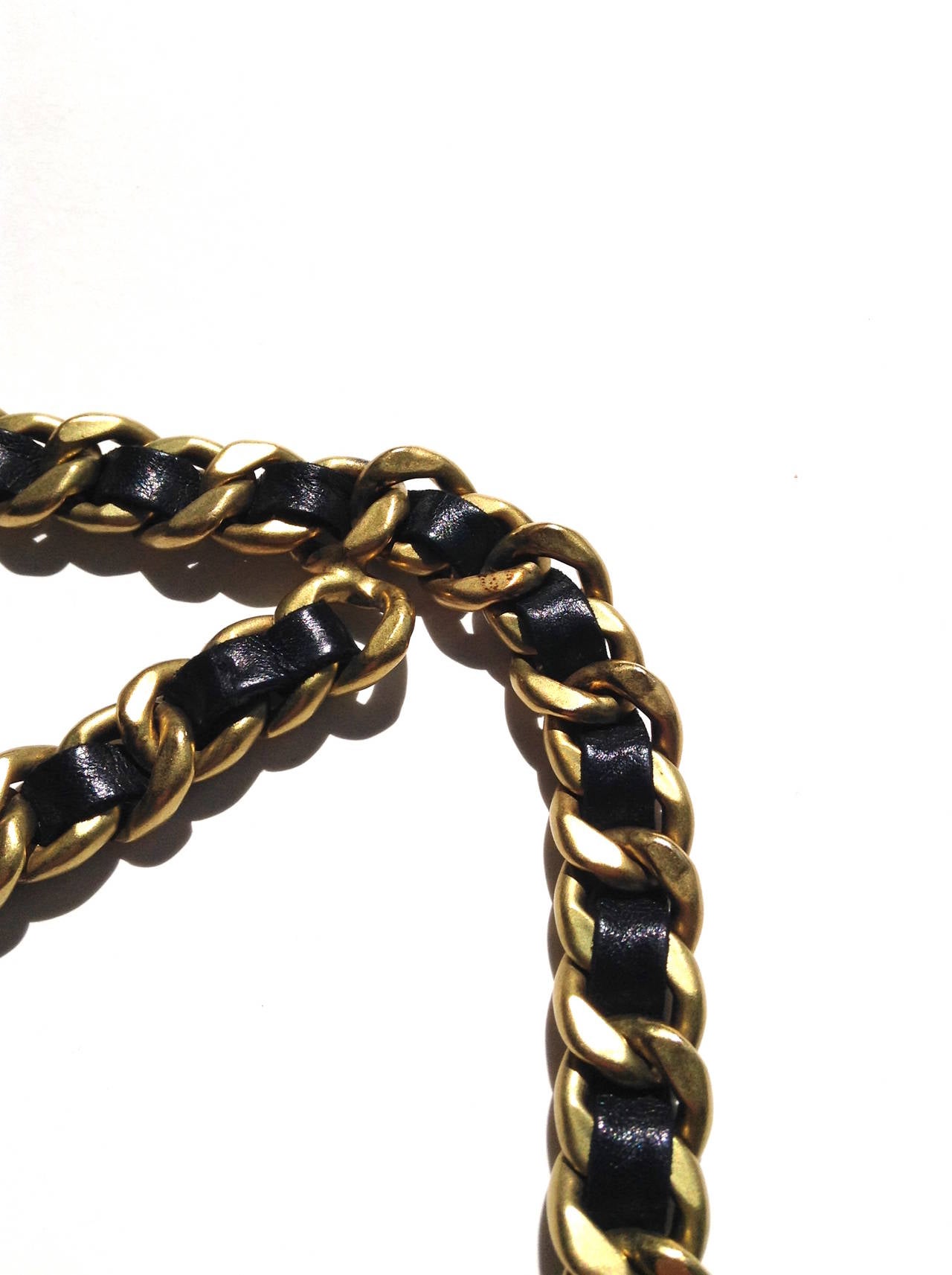 Vintage CHANEL, double wrap, logo pendant gold chain belt. This amazing piece features black leather woven throughout the hardware, and a 'Chanel' pendant. 

Measurements: 44