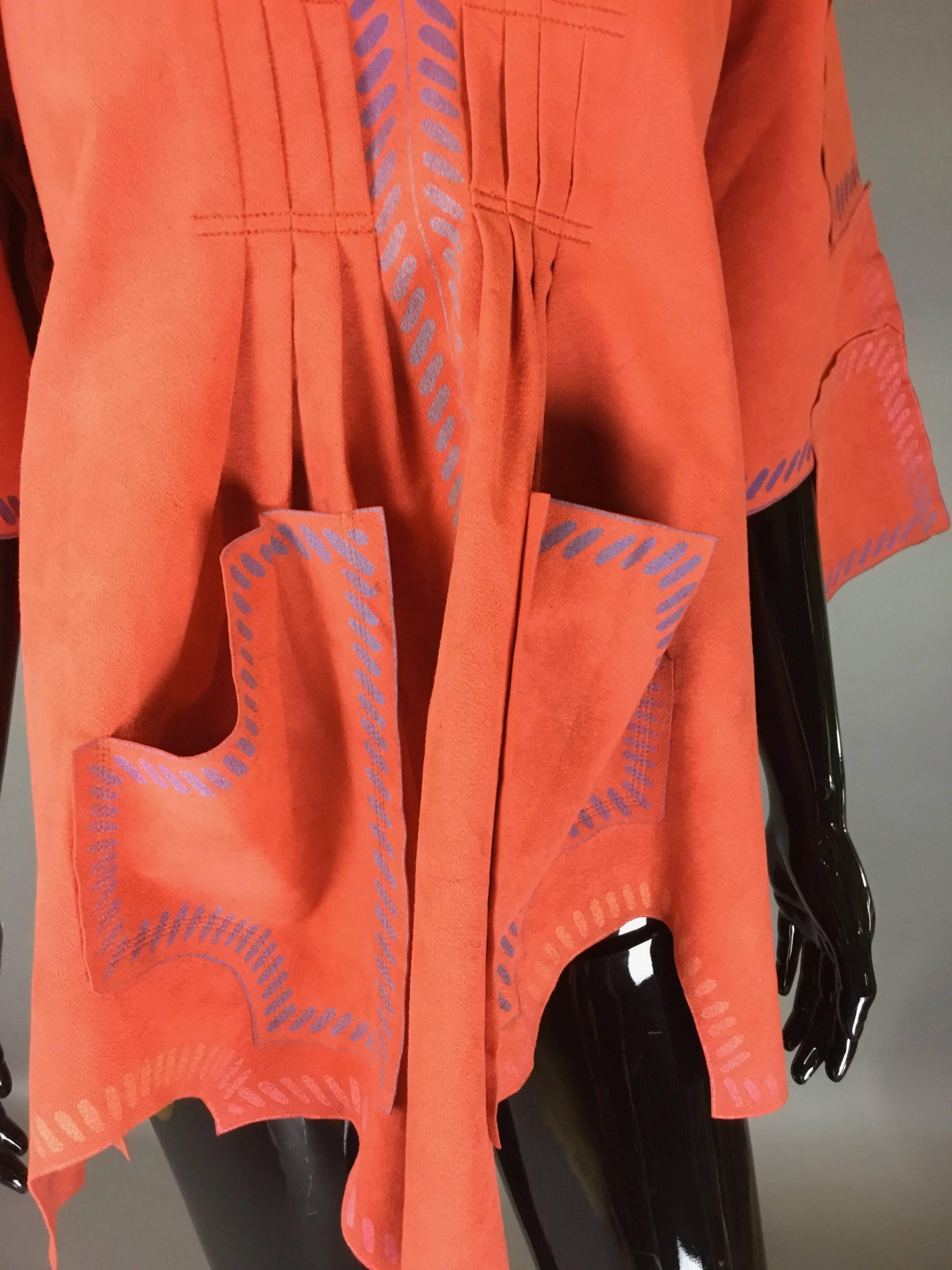 Super rare piece by British designer Zandra Rhodes. From her Cactus Cowboy collection of 1976. A beautiful coral orange ultra suede poncho style top. The hem cut as to look like an suede skin. A simple whipstitch print in pink and lavender around