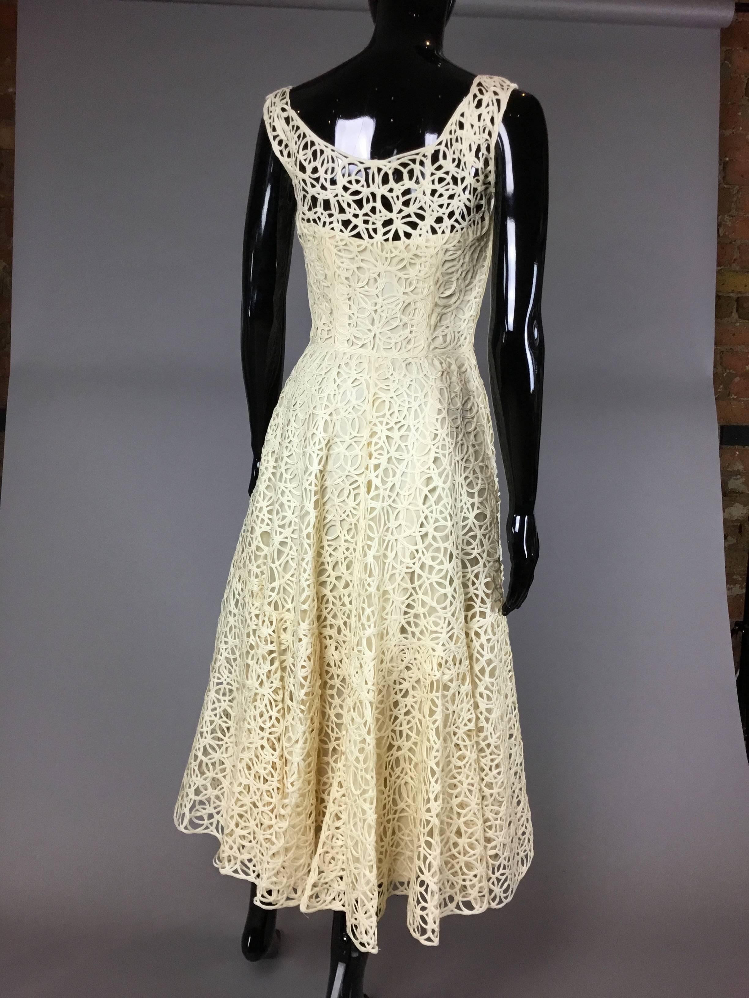an incredible cream 50s dress constructed entirely from a looped ribbon material. It has an integral lining with corset like boning at the waist and bust, and a side zip. The skirt is full towards the hem, creating a lovely feminine shape. 